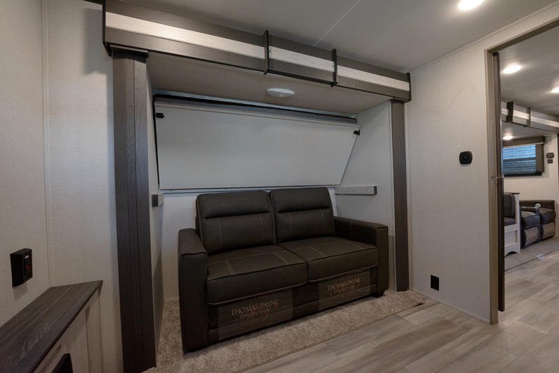 RV rental interior: a cozy brown sofa awaits under a neatly folded murphy bed. Ideal living space for your travels.. Keystone RV Sprinter Limited 2021