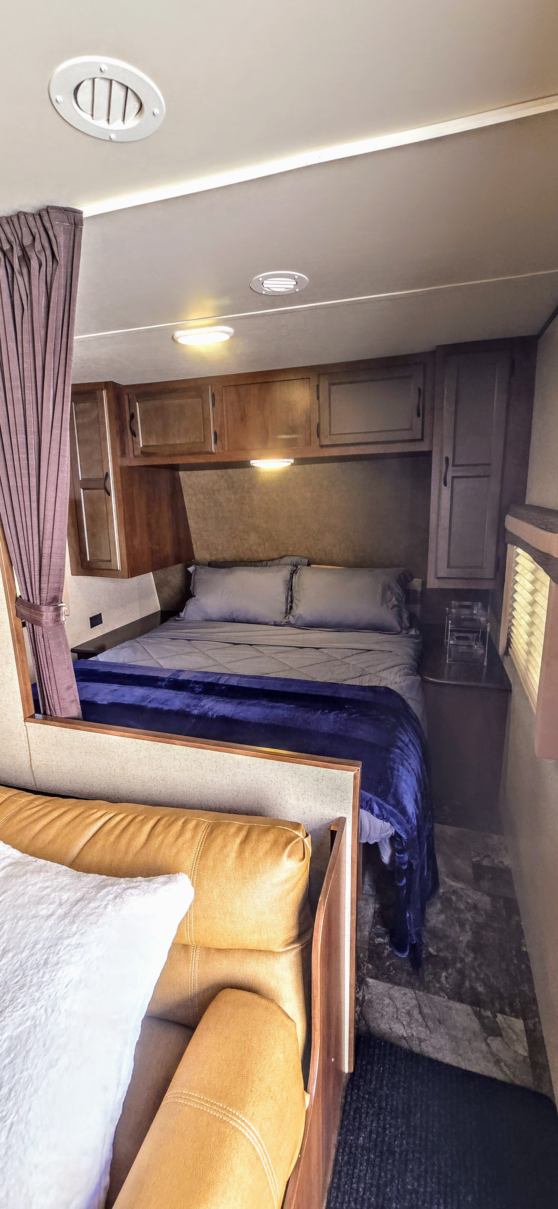 Inside an RV rental: a compact bedroom featuring a comfortable bed, storage cabinets, and an inviting leather seat.. Jayco Jay Flight 2015