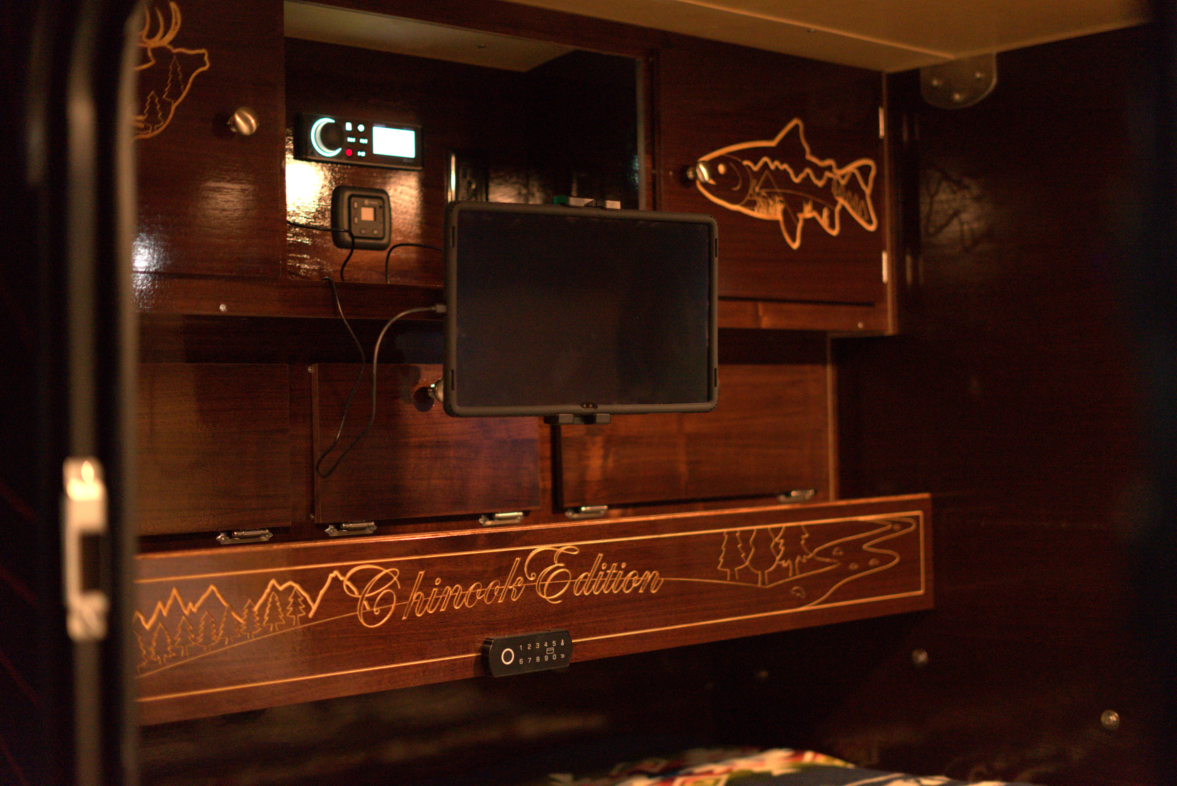 RV rental's custom wood interior: "Chinook Edition" etched panel, nature art (deer, fish), display, and keypad.. Teardrops NW Ranger 2025