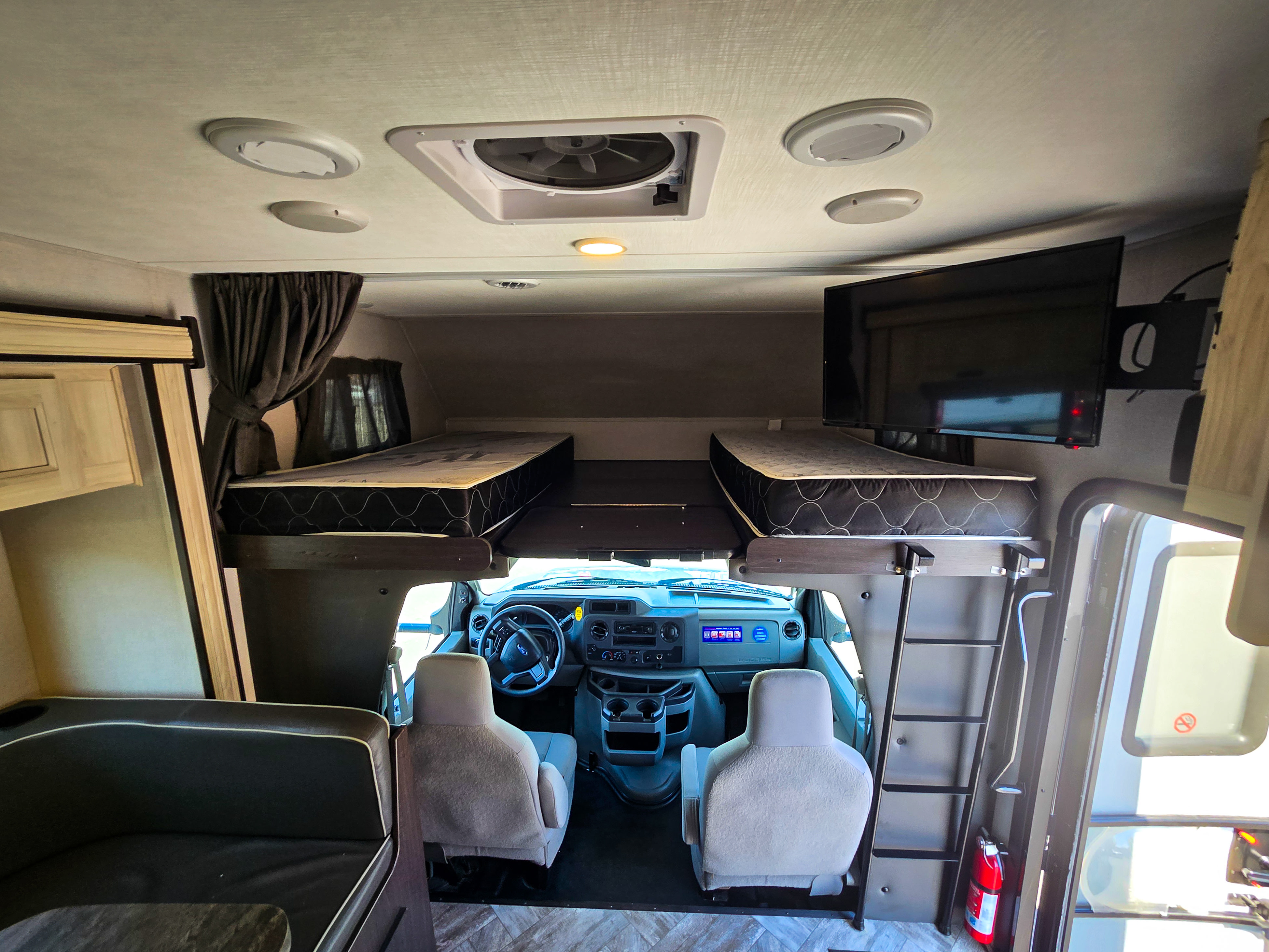 Interior of an RV rental: driver's cockpit, overhead bunk with two mattresses, a TV, and a dinette. Ready for travel!. Forester Classic 2022