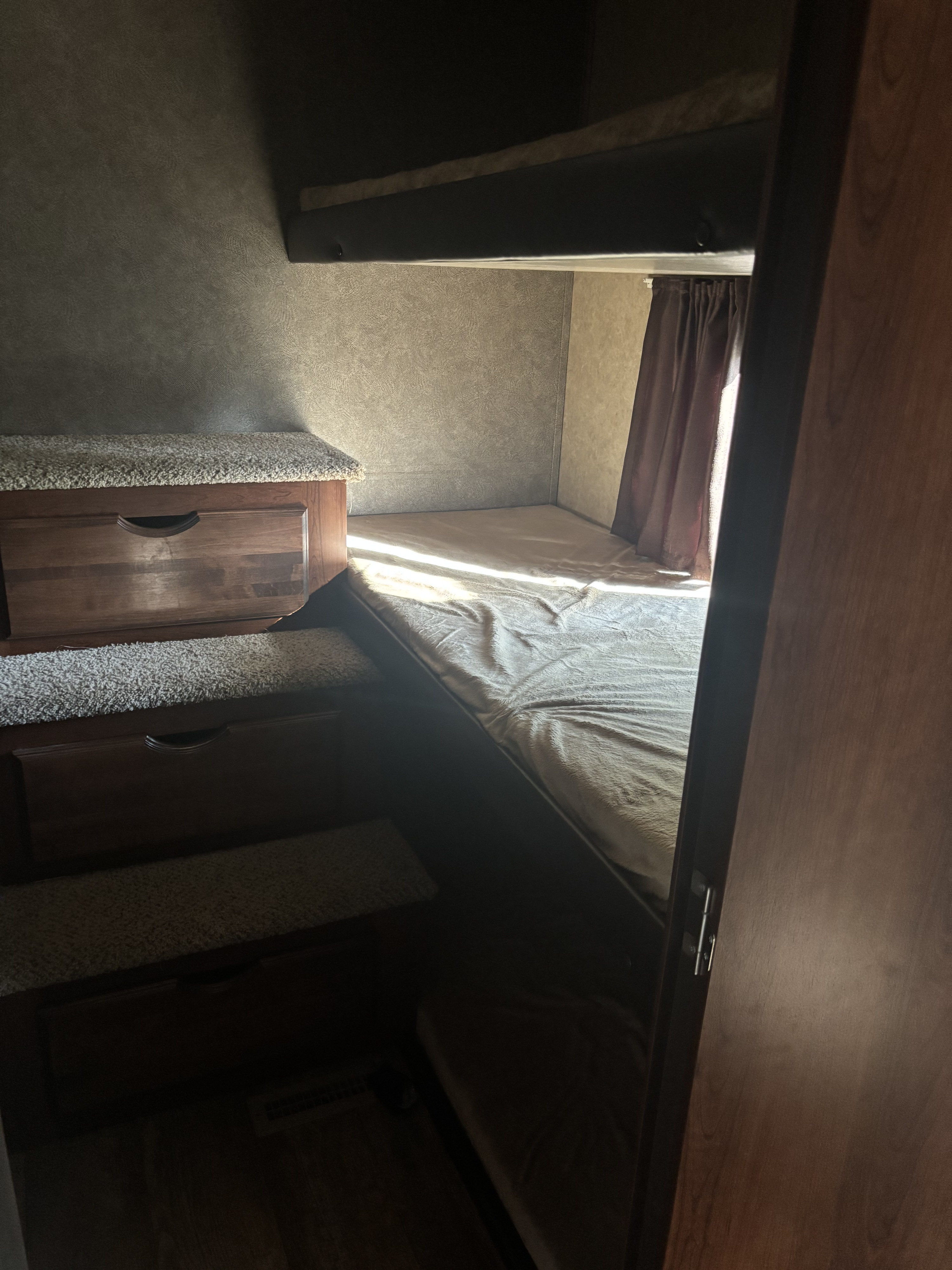 Inside an RV rental: a cozy bunk area featuring a lower bed, carpeted steps, and wood cabinetry for storage.. Jayco Eagle HT 2018