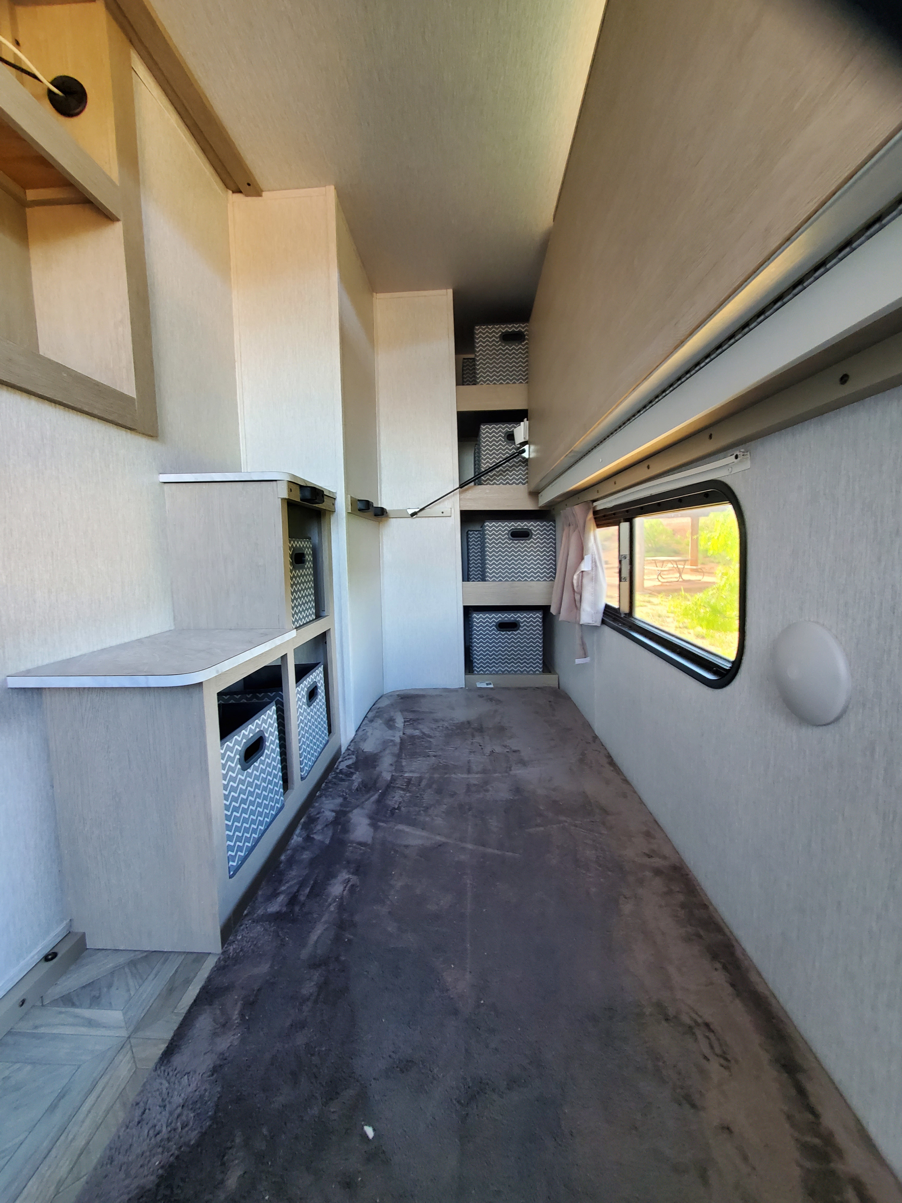 RV rental: Compact interior showing a bed, built-in storage with bins, and a window looking outdoors.. Forest River Salem Platinum 2024