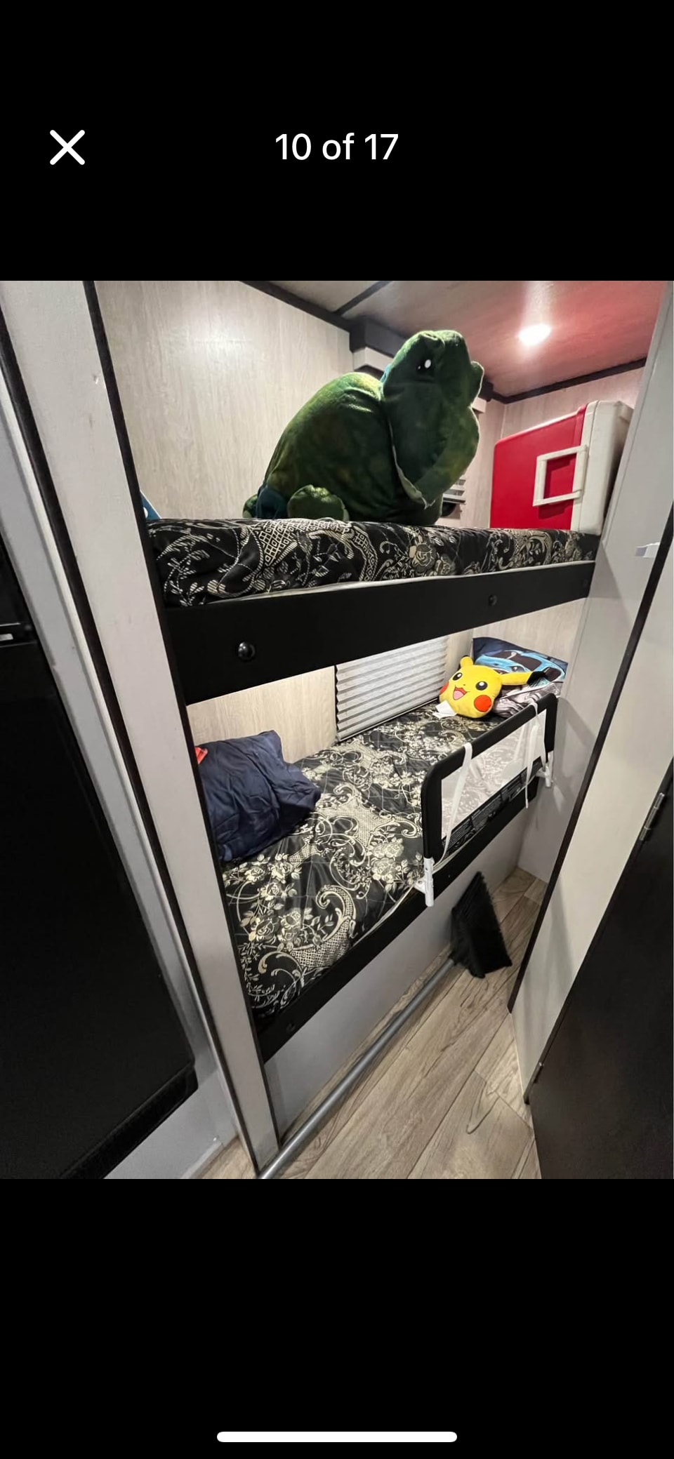 Inside an RV rental: Two cozy bunk beds, the top with a large green plush, the bottom with a Pikachu and safety rail.. Genesis Supreme surfside travel traiker 2024
