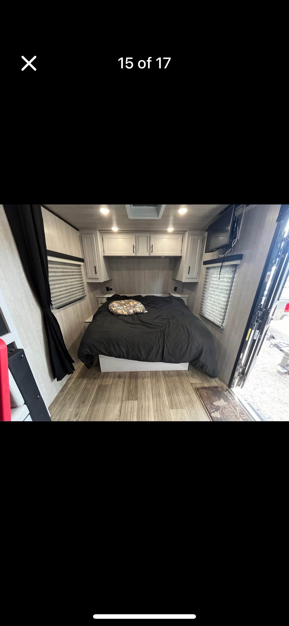 Experience comfort in this RV rental bedroom: features a large bed, overhead cabinets, and wood-look flooring. Ideal for travelers.. Genesis Supreme surfside travel traiker 2024