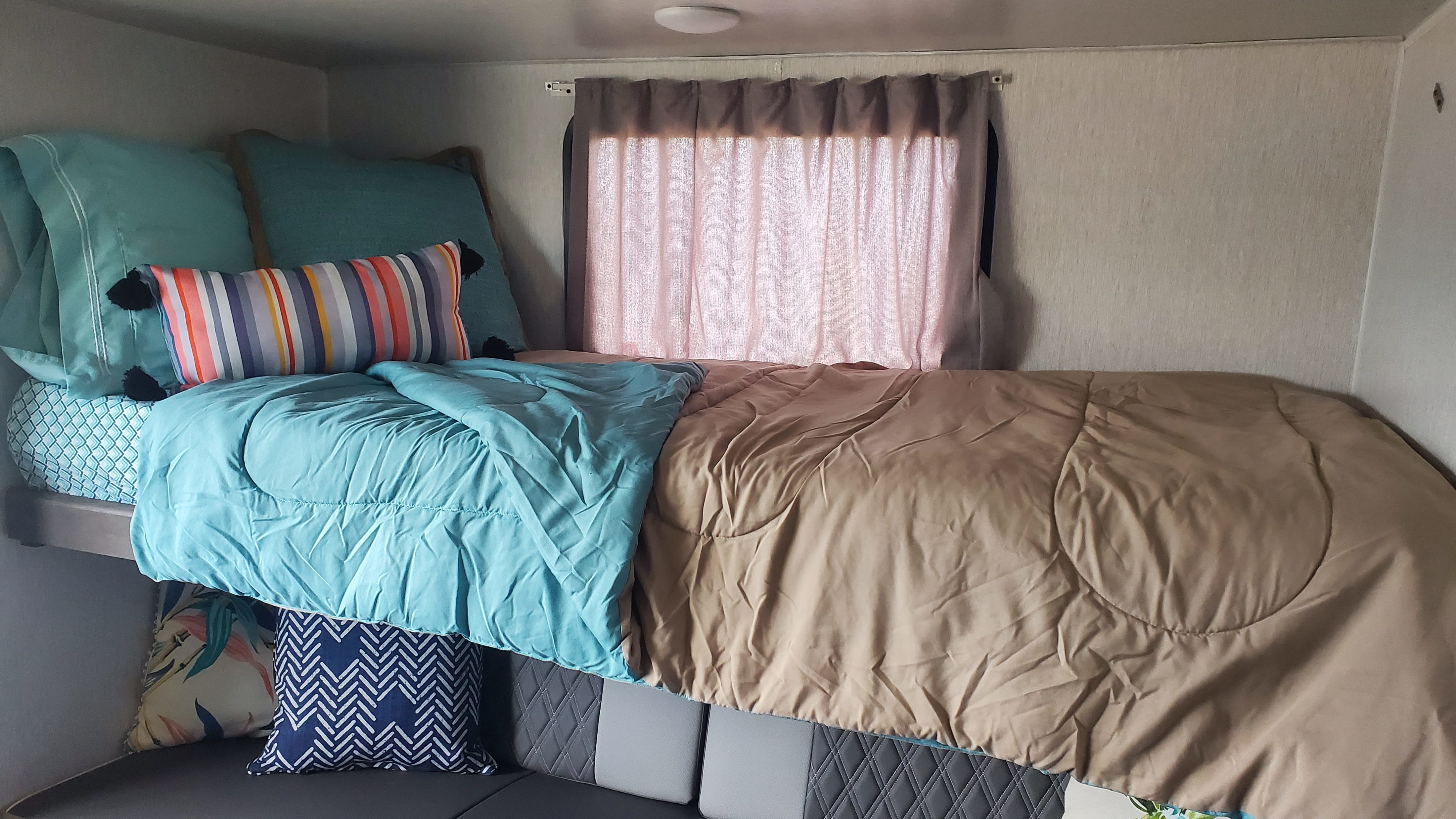 Comfortable bunk beds in an RV rental, featuring turquoise & tan bedding with decorative pillows. Ideal for family travel.. Forest River Salem 2022