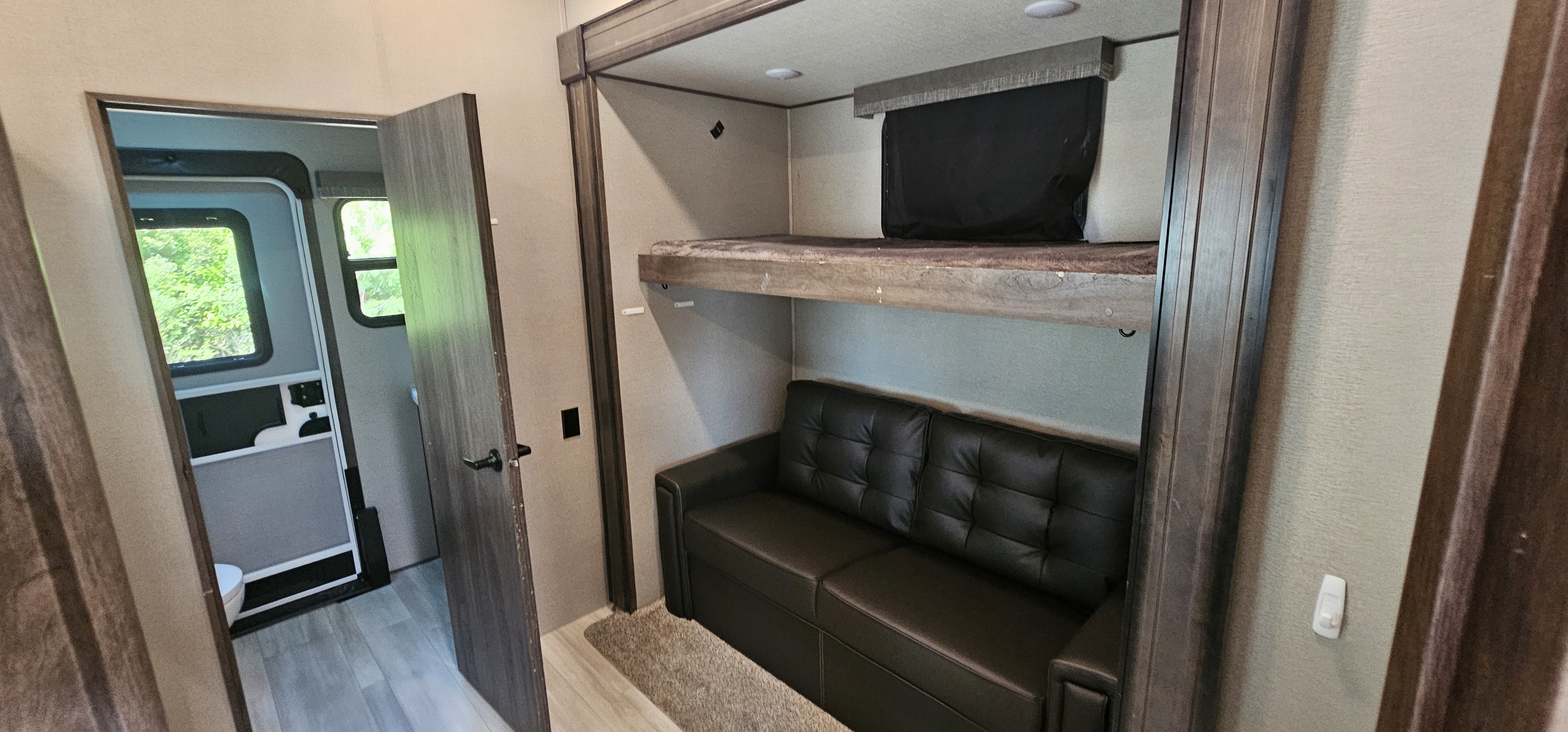 Spacious RV rental interior featuring comfortable bunk beds over a sofa, with a partial view into another room.. Grand Design Solitude S-Class 2022