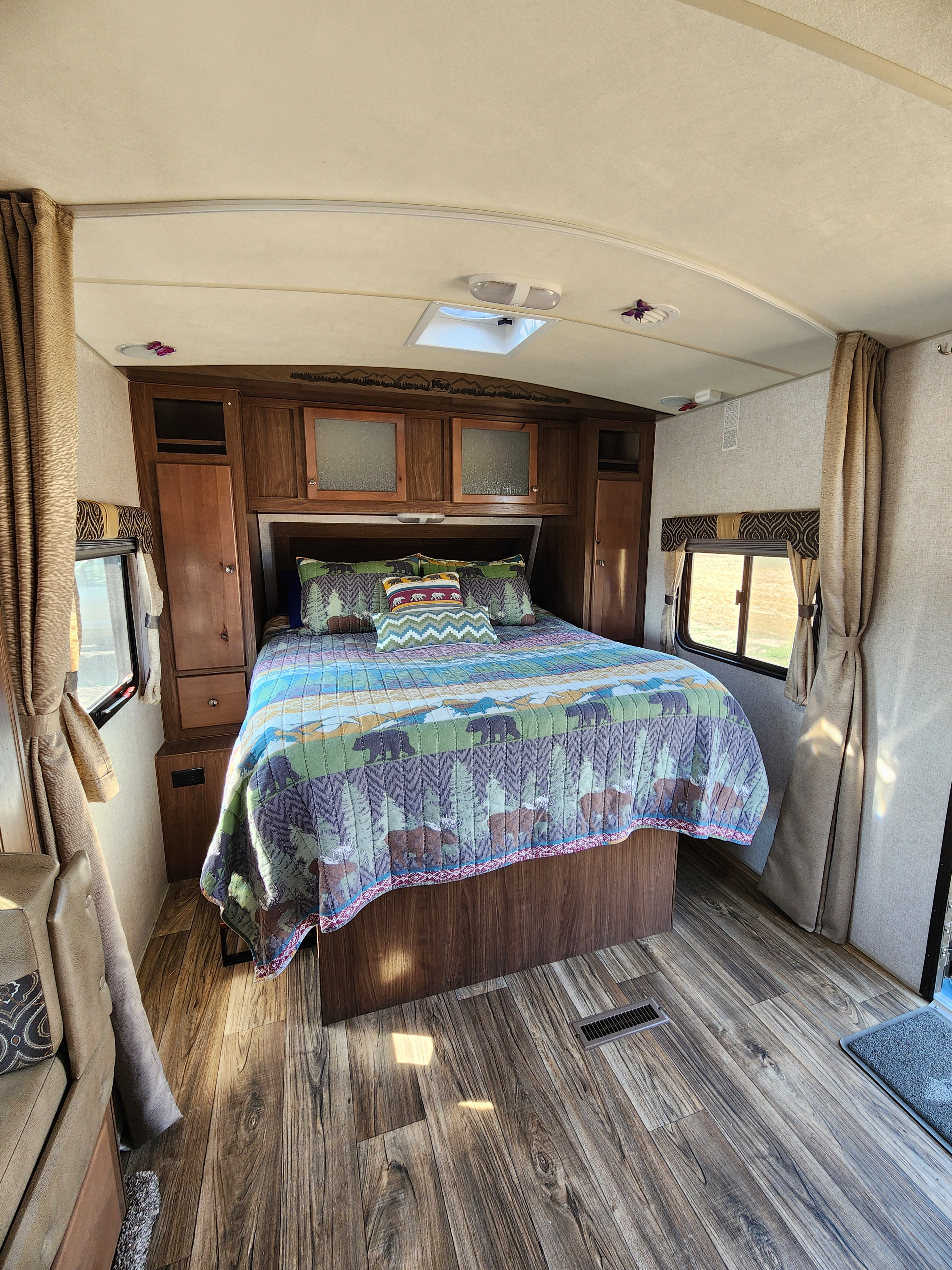 RV rental bedroom: a cozy space with a bed, bear/moose quilt, wood cabinetry, and wood-look flooring.. Nash Nash Trailer 2021
