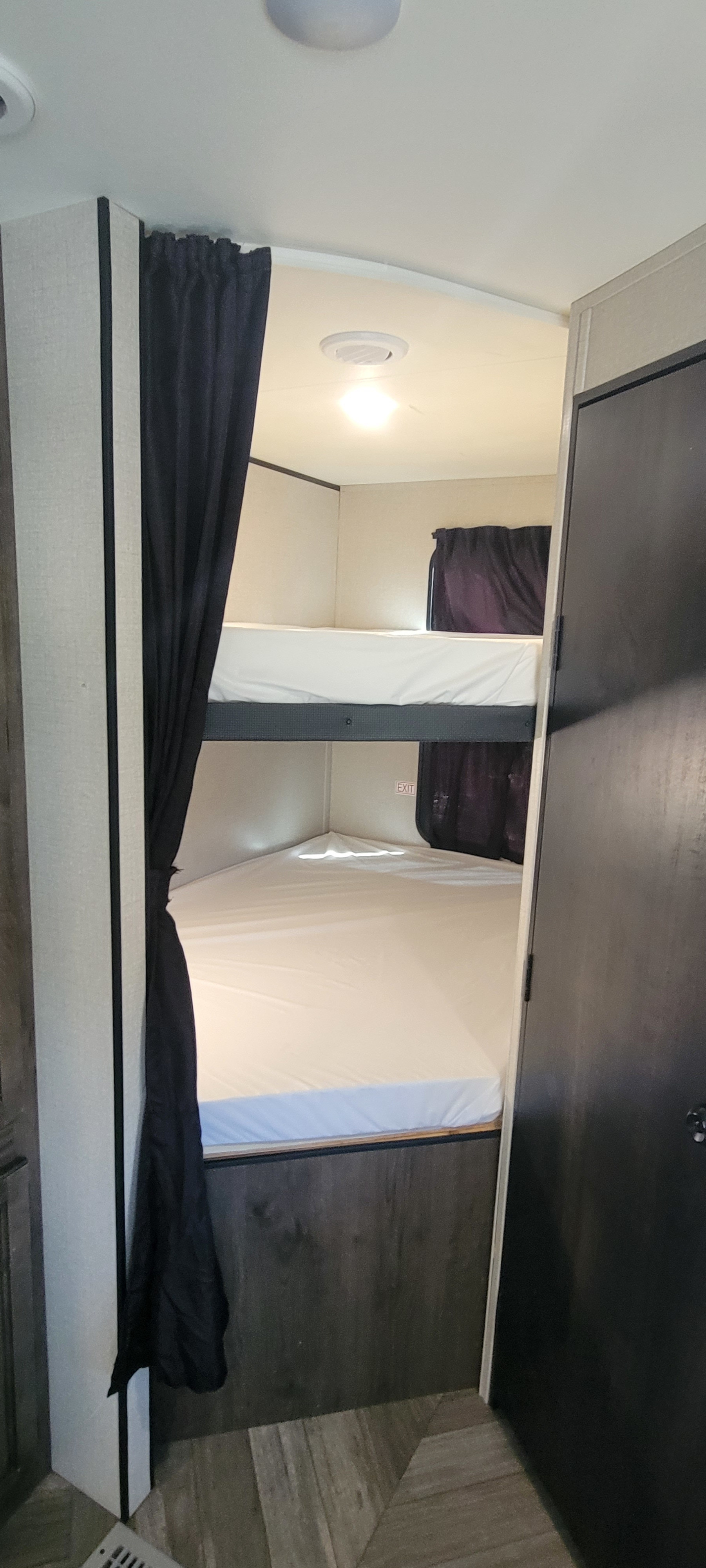 This RV rental features a comfortable bunk bed setup with white mattresses and curtains, offering a cozy sleeping space.. Highland Ridge RV Olympia 2022