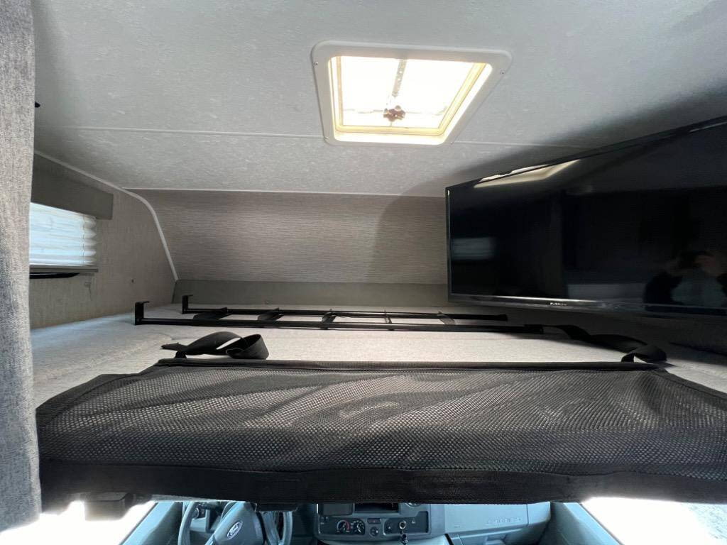 RV rental interior featuring a cab-over bunk, TV, skylight, and safety net, perfect for family adventures.. Coachman Leprechaun 2022