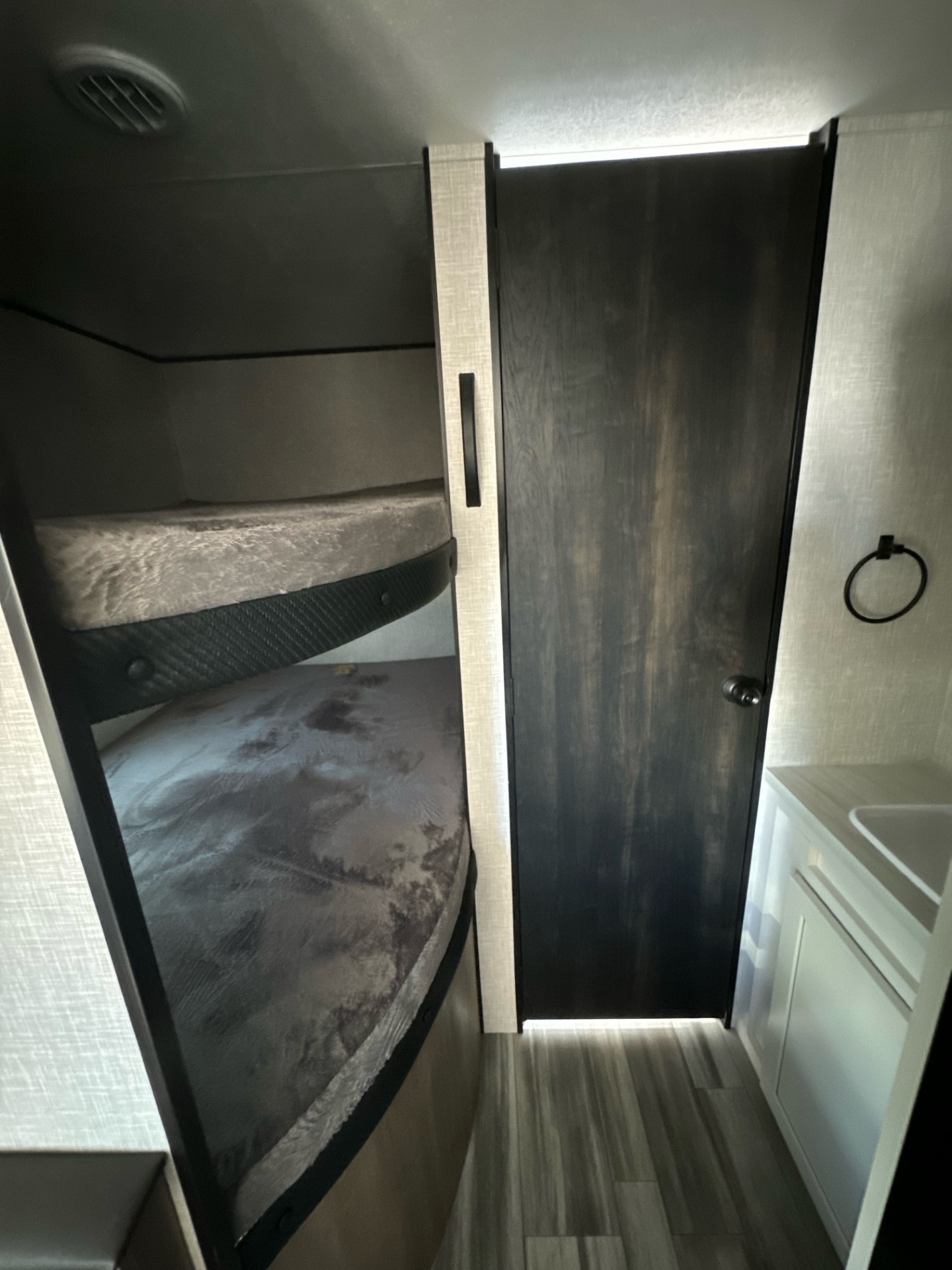 Inside a modern RV rental: well-designed bunk beds, a dark bathroom door, and a compact sink vanity.. Jayco Jay Flight SLX 2024