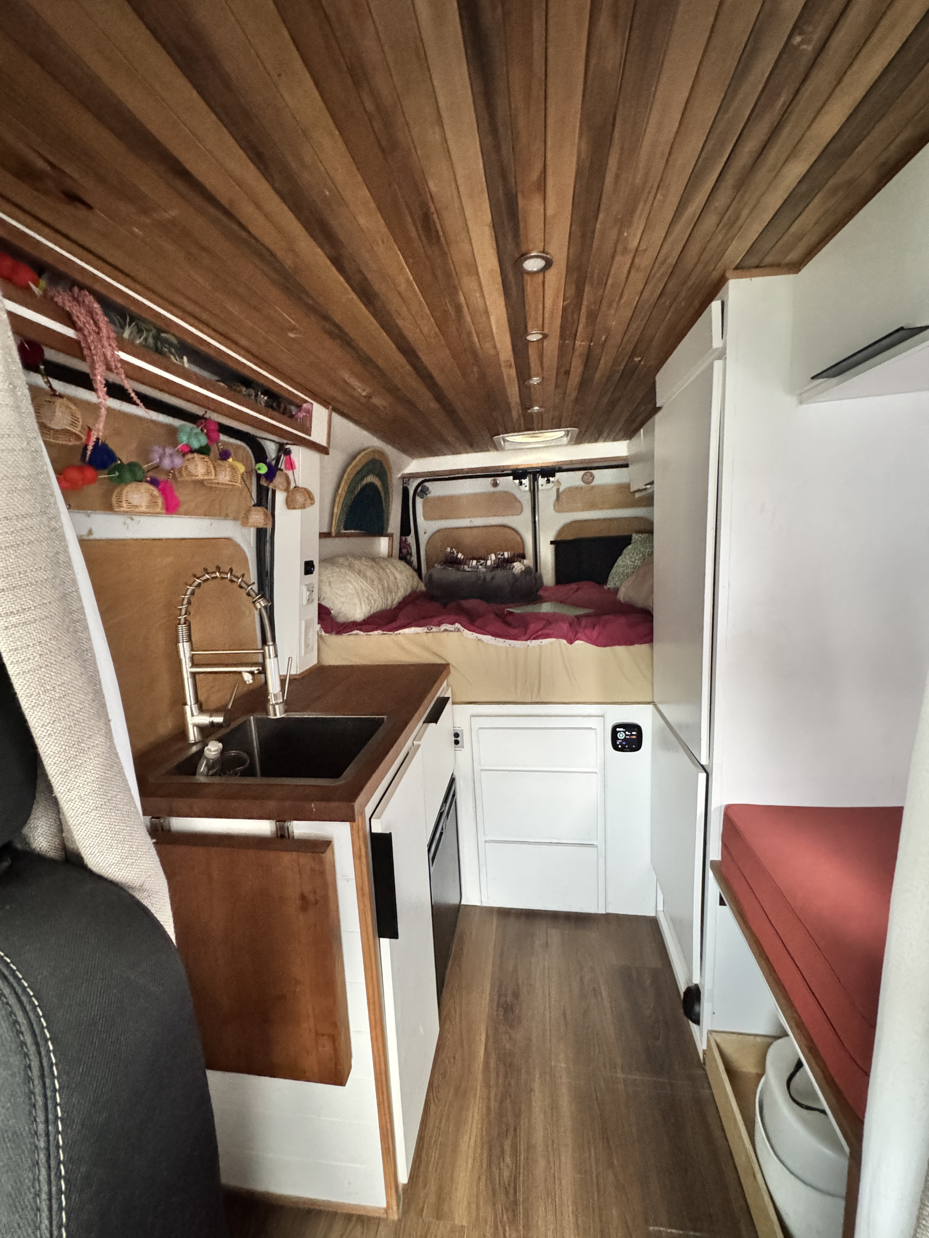 Spacious camper van interior, ideal for an rv rental, featuring a kitchenette, rear bed, and cozy wooden ceiling.. Dodge Ram 1500 2020