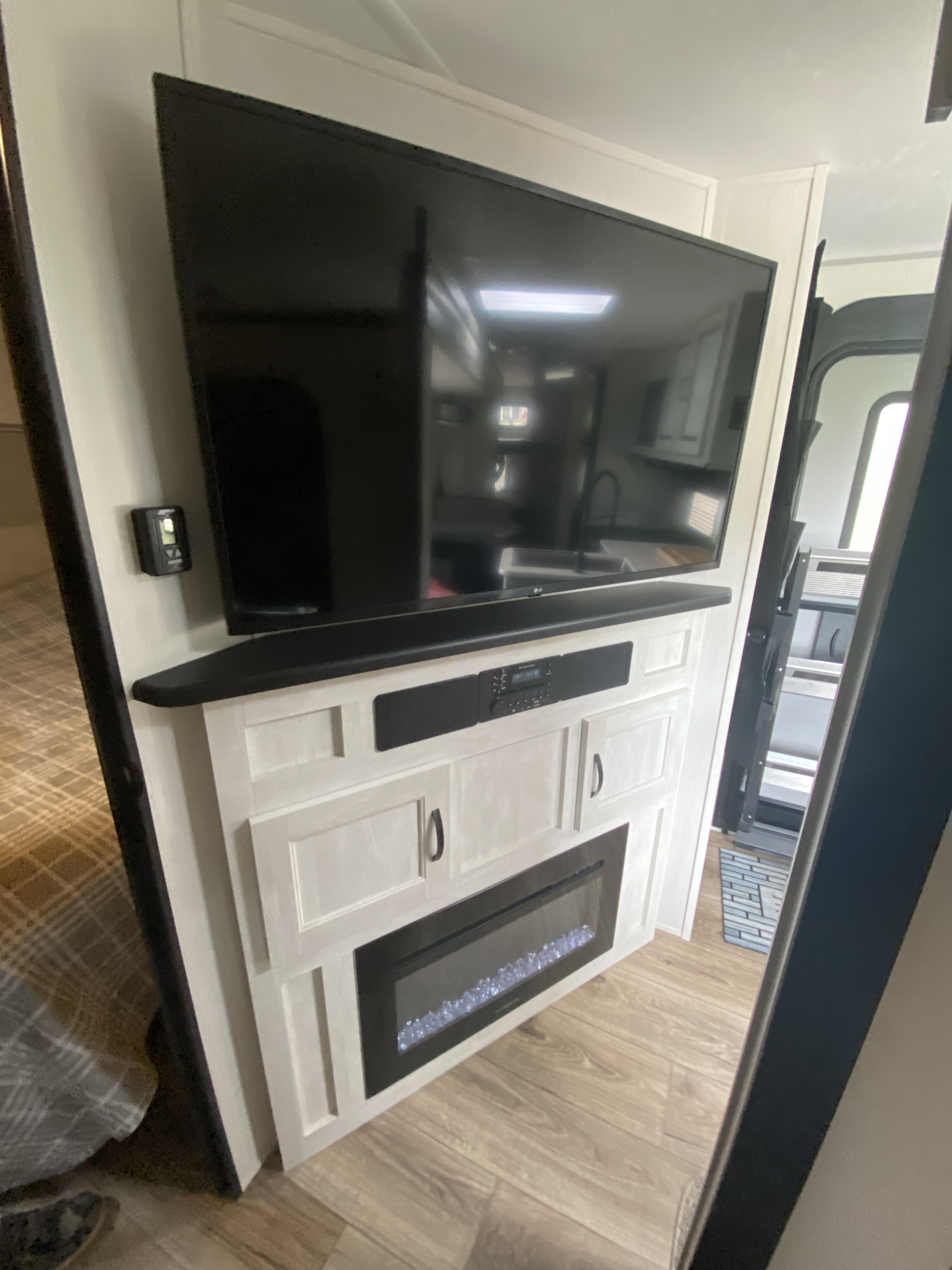 RV rental interior: modern entertainment center with a large TV, soundbar, and electric fireplace, creating a homey atmosphere.. Forest River Other 2021