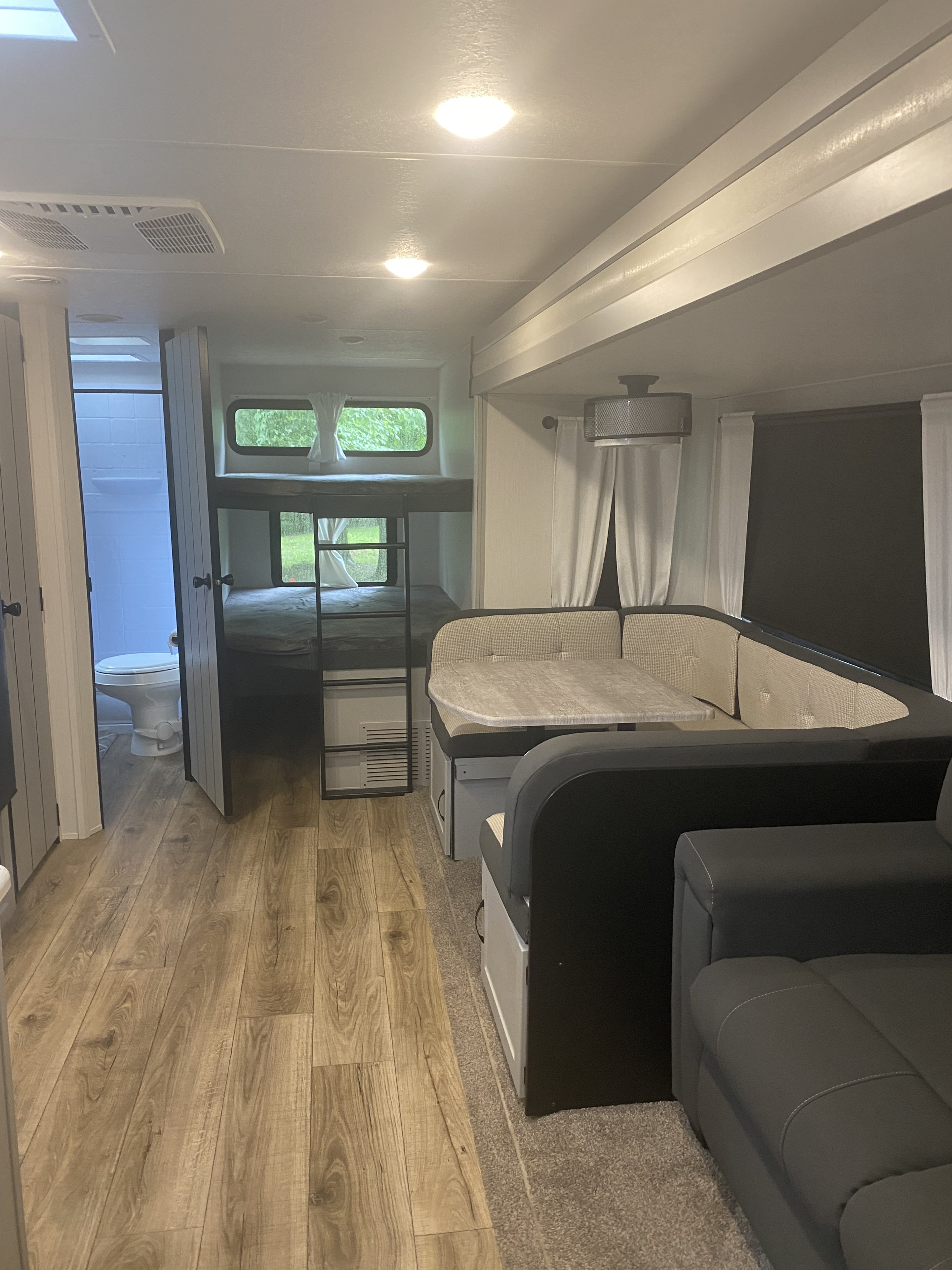 Clean RV rental interior featuring bunk beds, dinette, sofa, and a bathroom. Modern design with wood floors and carpet.. Forest River Other 2021