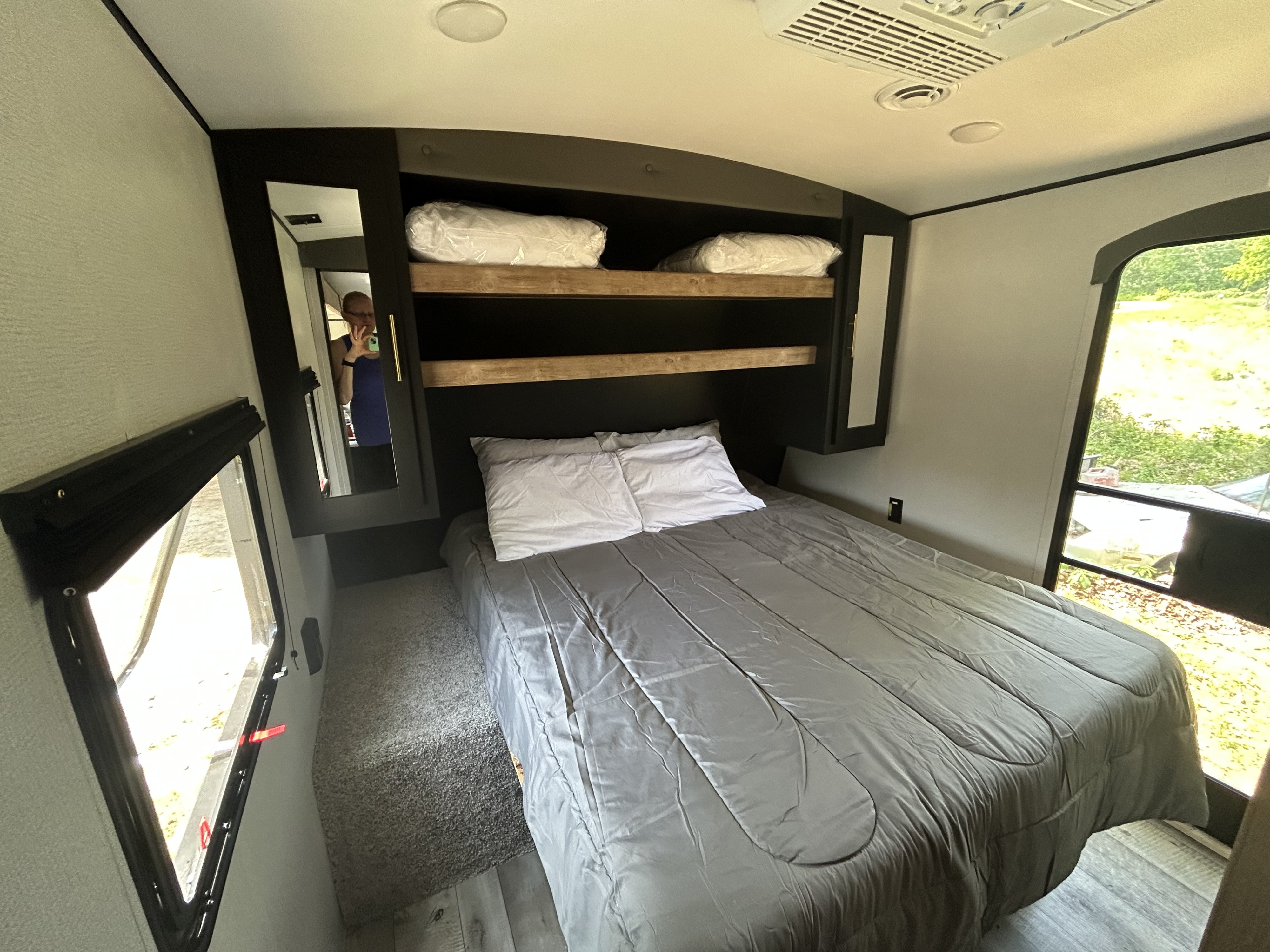 Relax in this cozy RV rental bedroom. It features a comfy bed, overhead storage, and windows for light.. Keystone RV Springdale 2022
