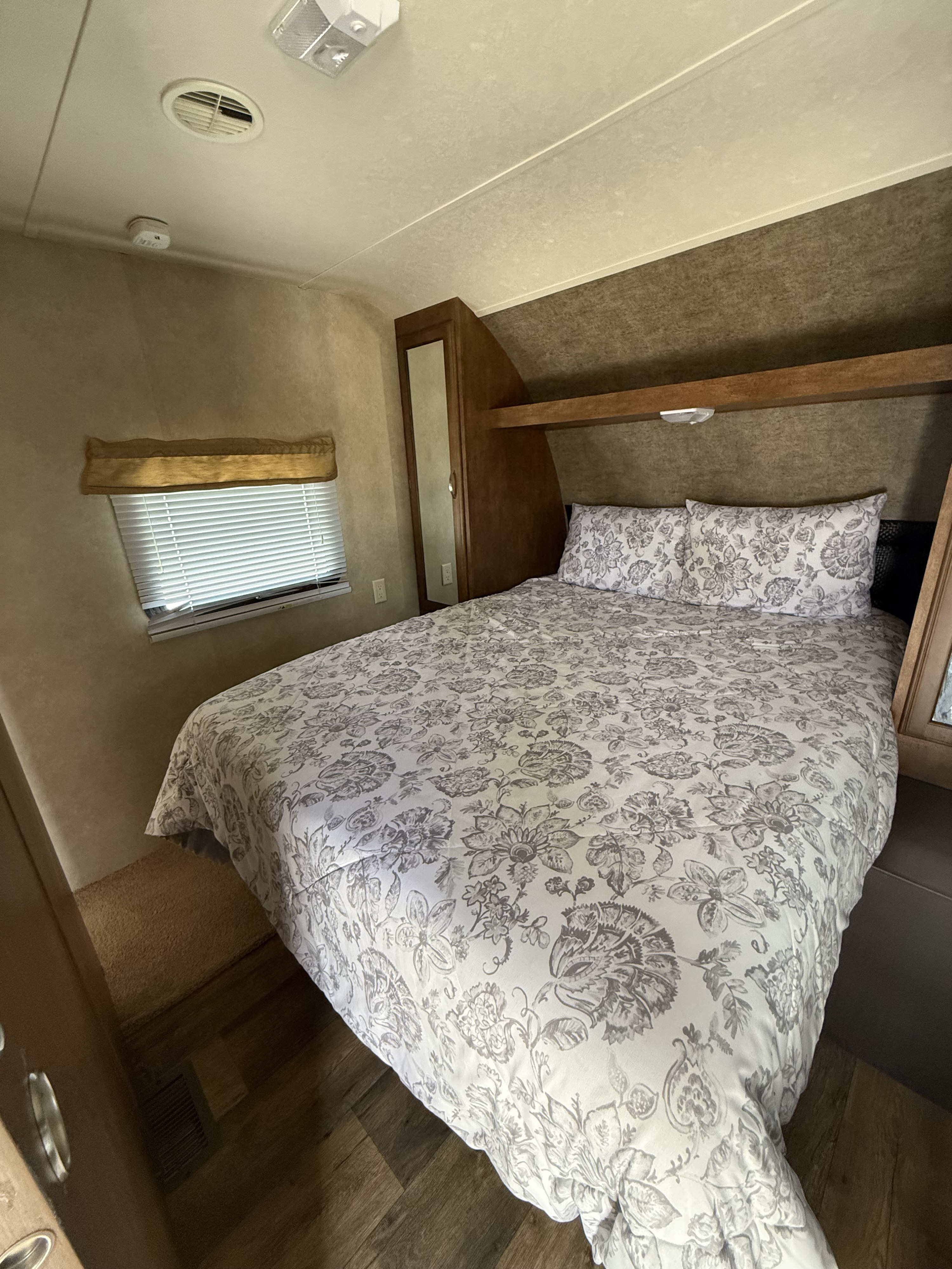 Cozy RV rental bedroom with floral bedding, window, and convenient built-in storage.. Forest River Wildwood 2016