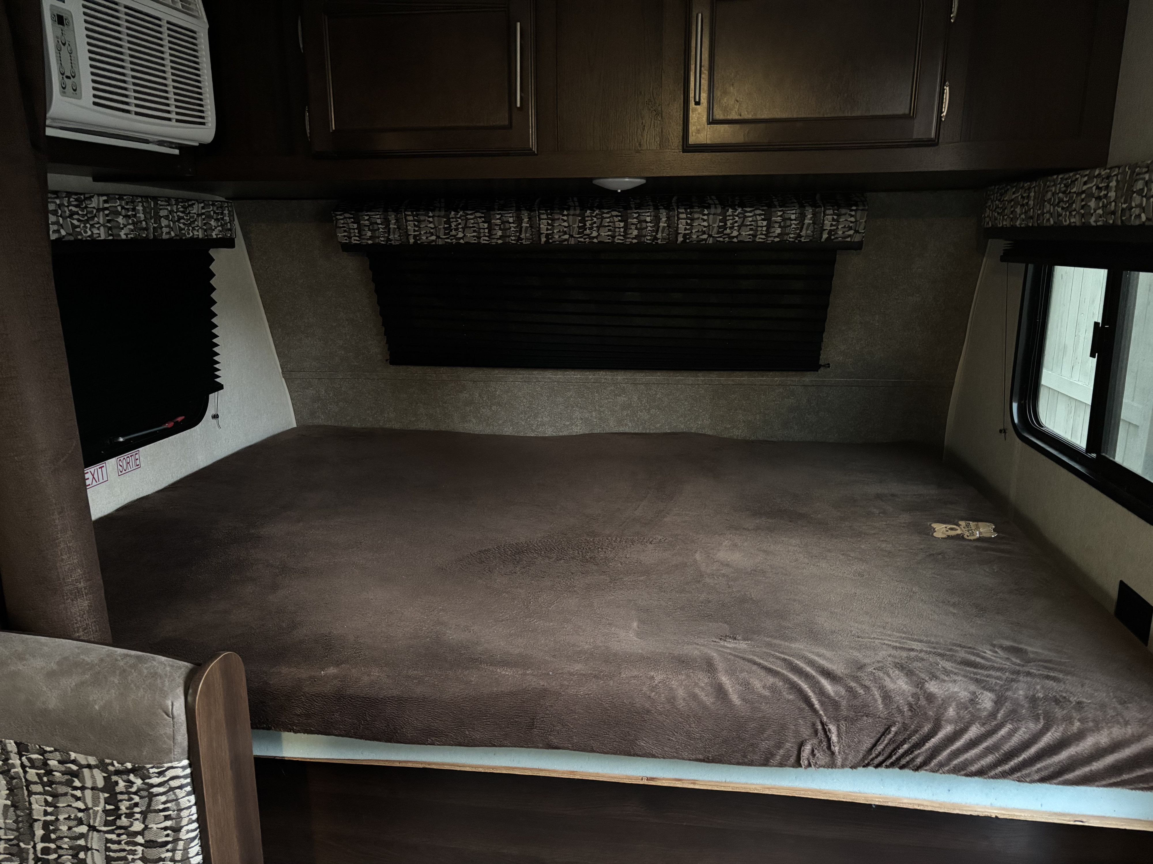 Inside an RV rental: Plush brown bed, overhead cabinets, and AC unit create a comfortable sleeping space in this camper.. Jayco Jay Flight SLX 2019