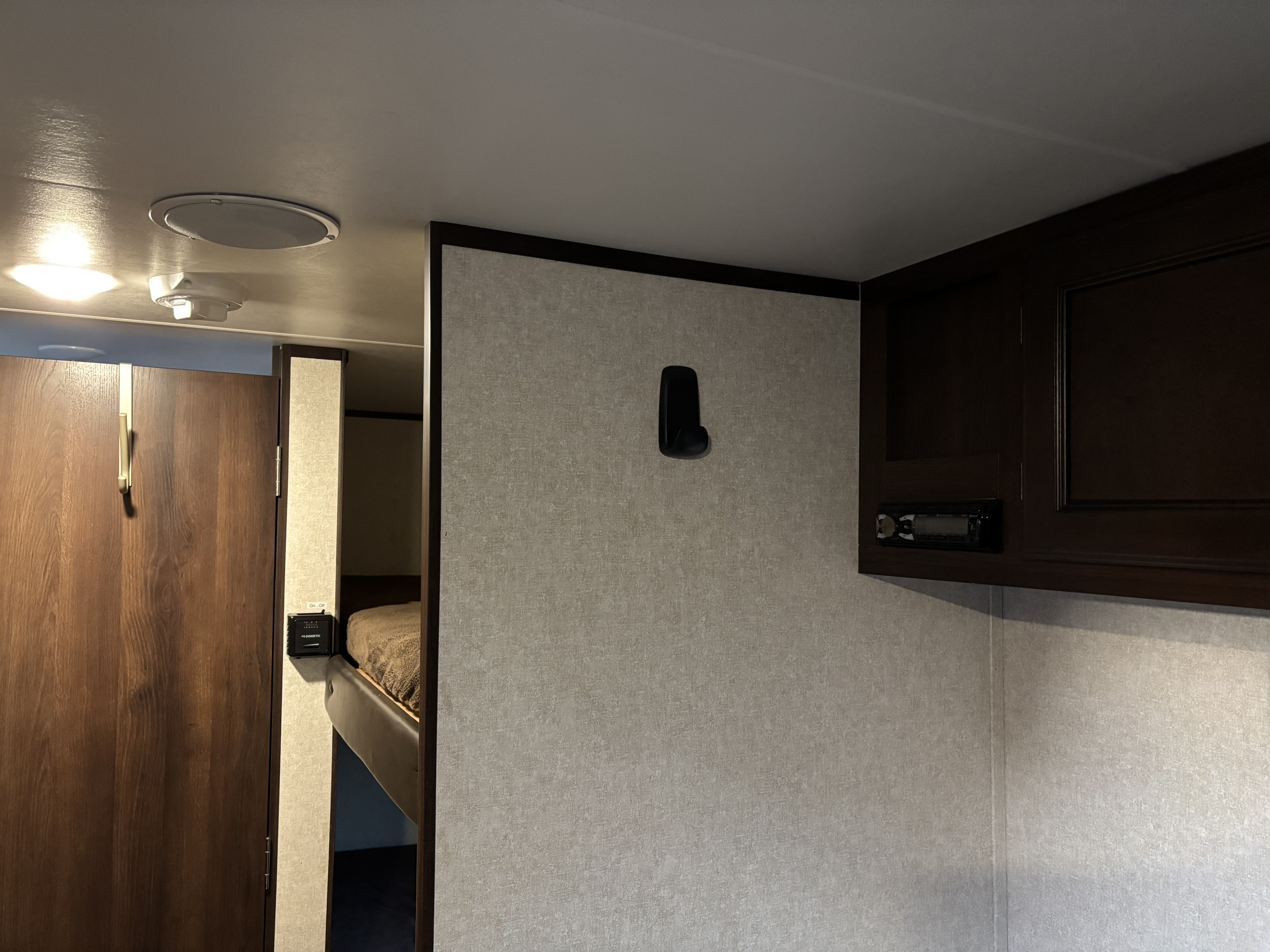 Interior of an RV rental: a compact recreational vehicle with bunk beds, a door, ceiling lights, and an embedded stereo system.. Jayco Jay Flight SLX 2019