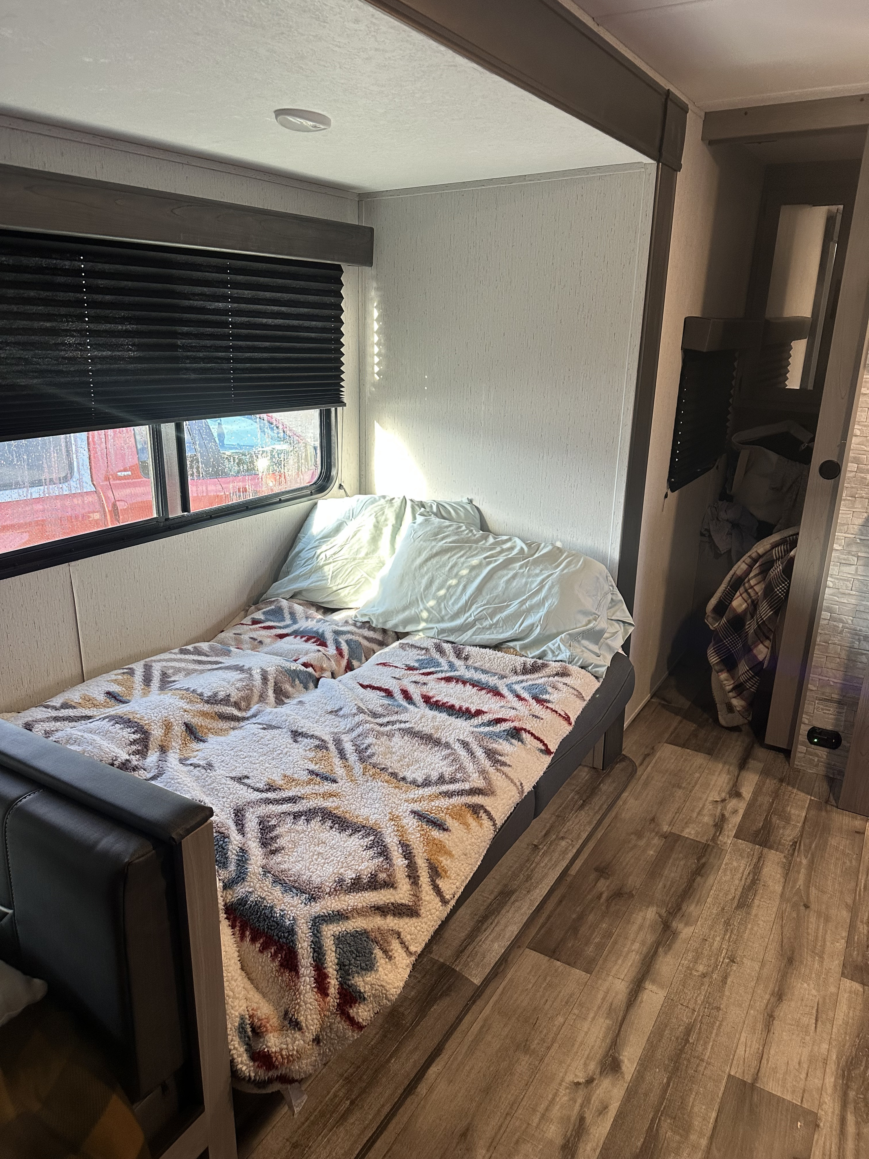 Cozy RV rental bedroom with a bed, patterned blanket, window blinds, and wood-look floor. Ideal for a travel adventure.. Coleman Lantern 263BHWE 263BHWE 2024