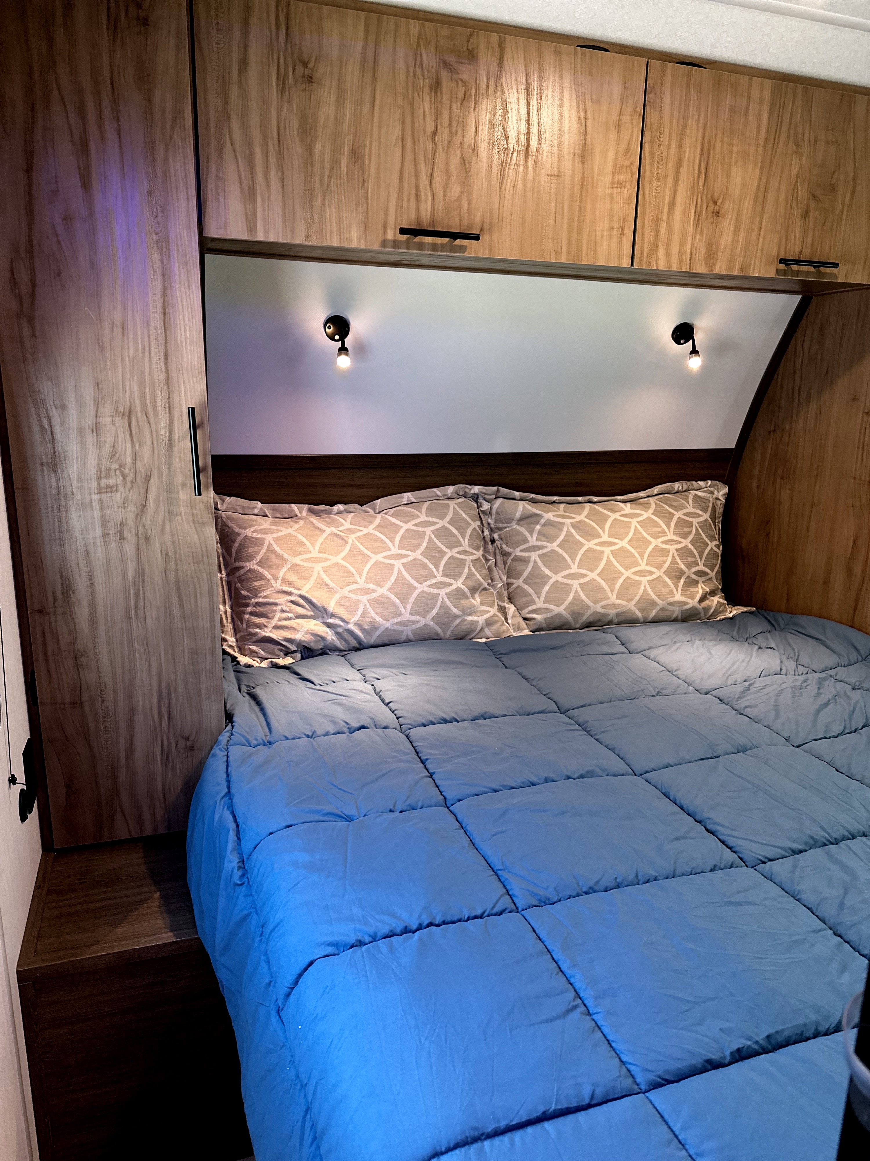 Cozy RV rental bedroom with wood cabinets, a comfy bed, and reading lights, perfect for travel.. Forest River Cherokee Black Label 2025