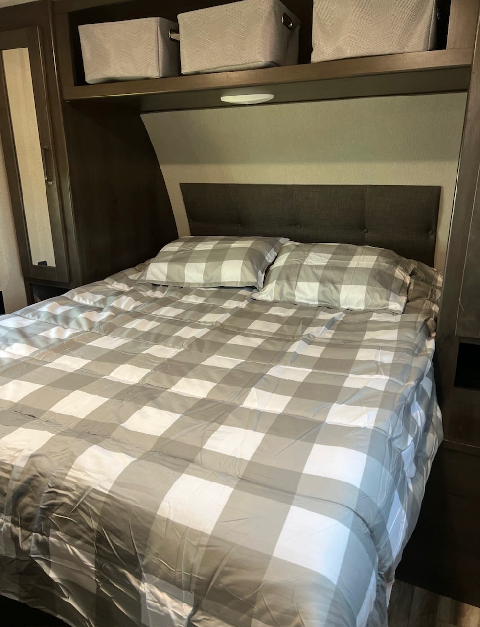 Cozy RV rental bedroom with plaid bedding, a comfy headboard, and handy overhead storage bins.. Grand Design Transcend Xplor 2021