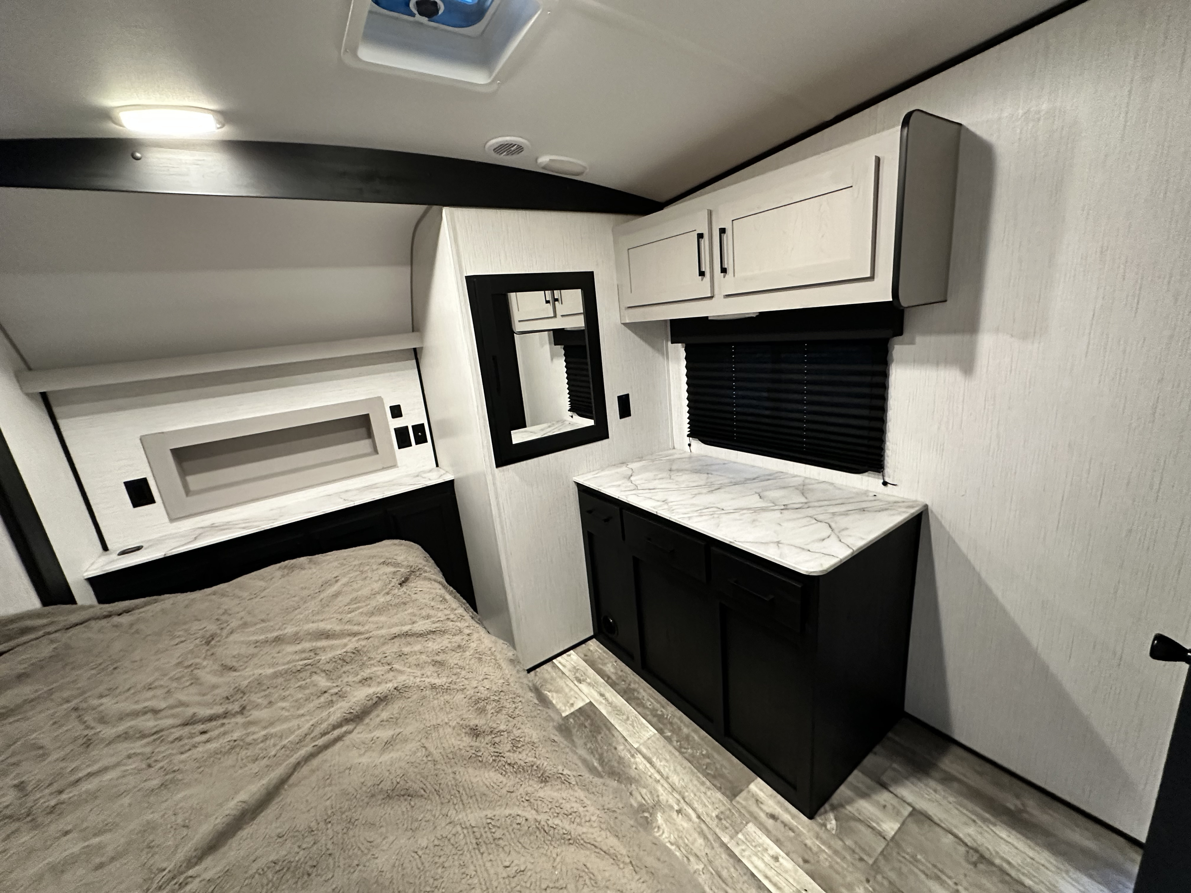 Spacious RV rental bedroom with modern black and white cabinetry, marble-look counters, mirror, and cozy bed. Ideal for road trips.. Heartland Fuel Toy Hauler 2022