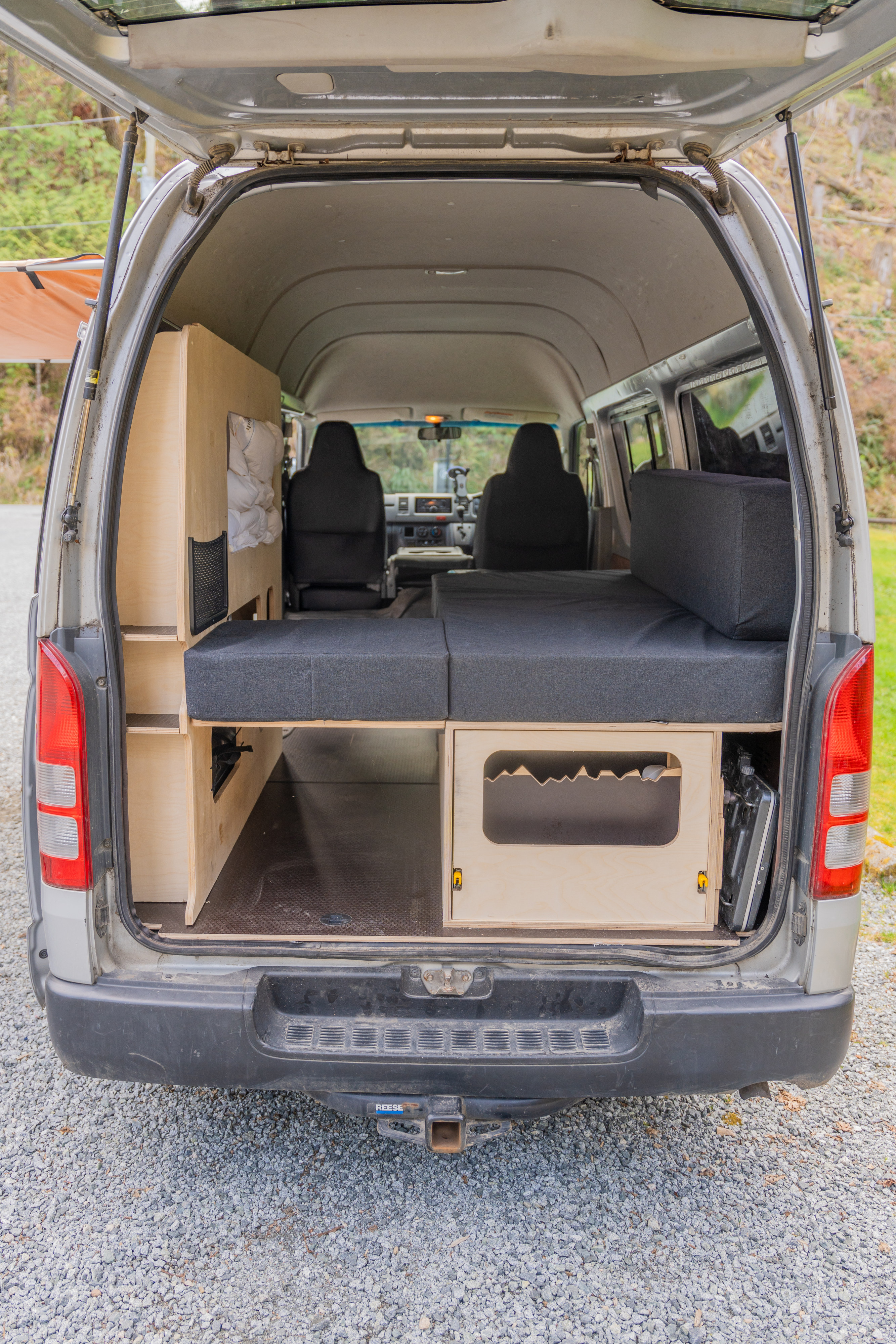 This RV rental showcases a custom campervan interior with a bed, shelving, and storage, ready for adventure.. Toyota HIACE 2006