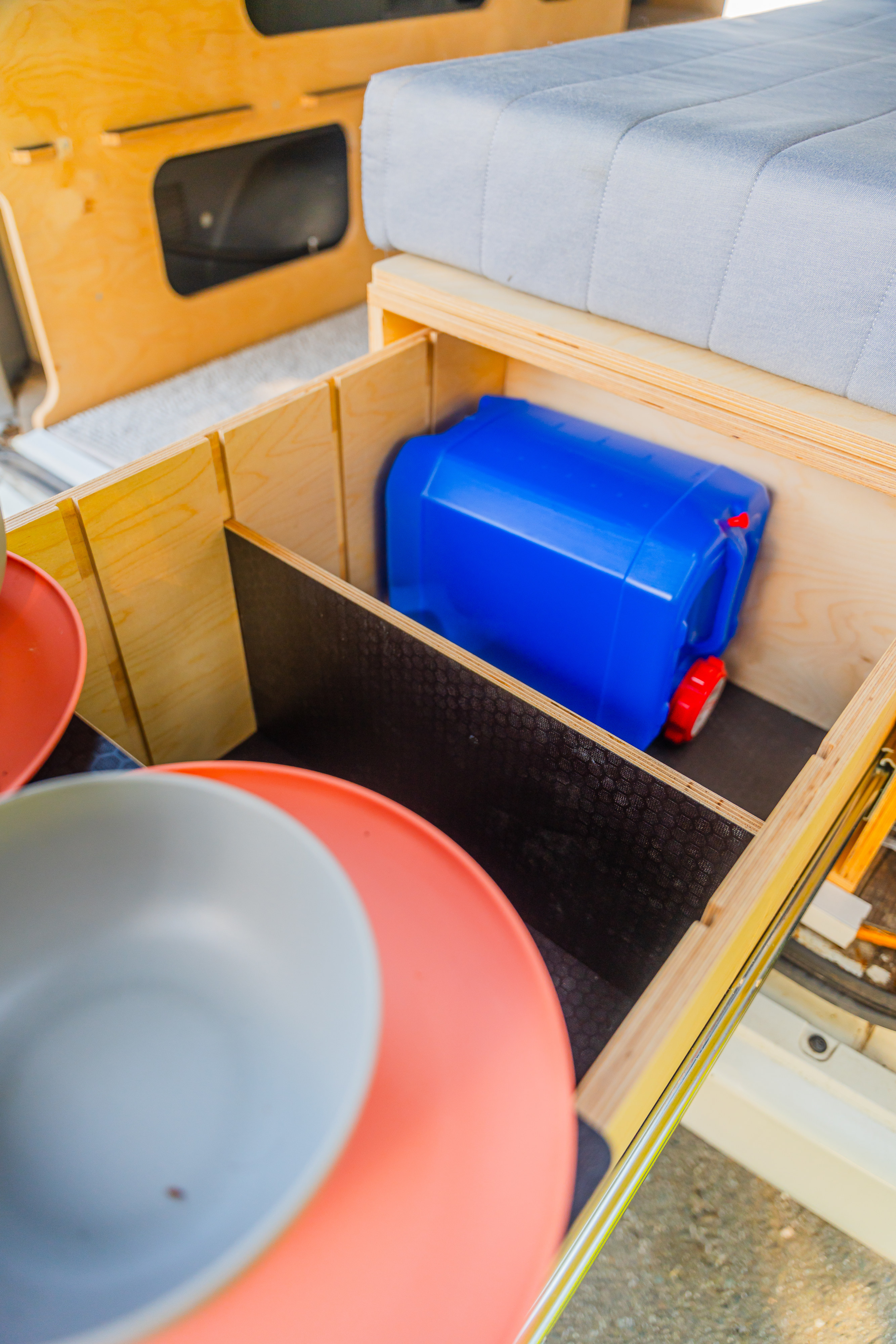 RV rental: Organized pull-out storage with dishes, water jug, and a cozy bed. Essential camper features.. Toyota Hiace 2005