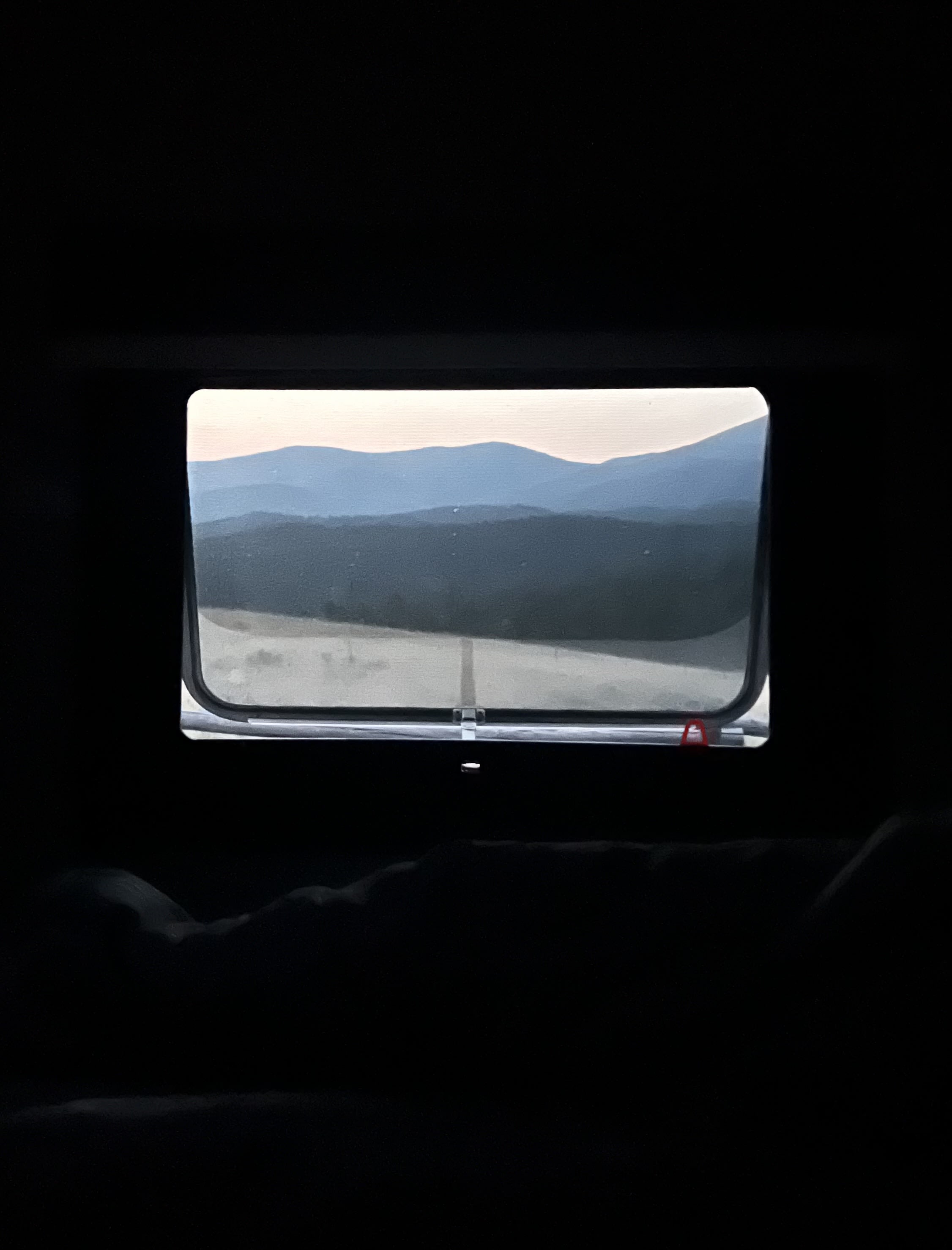 Layers of blue mountains are seen through a window from a dark RV rental interior.. Jayco Jay Feather 2021