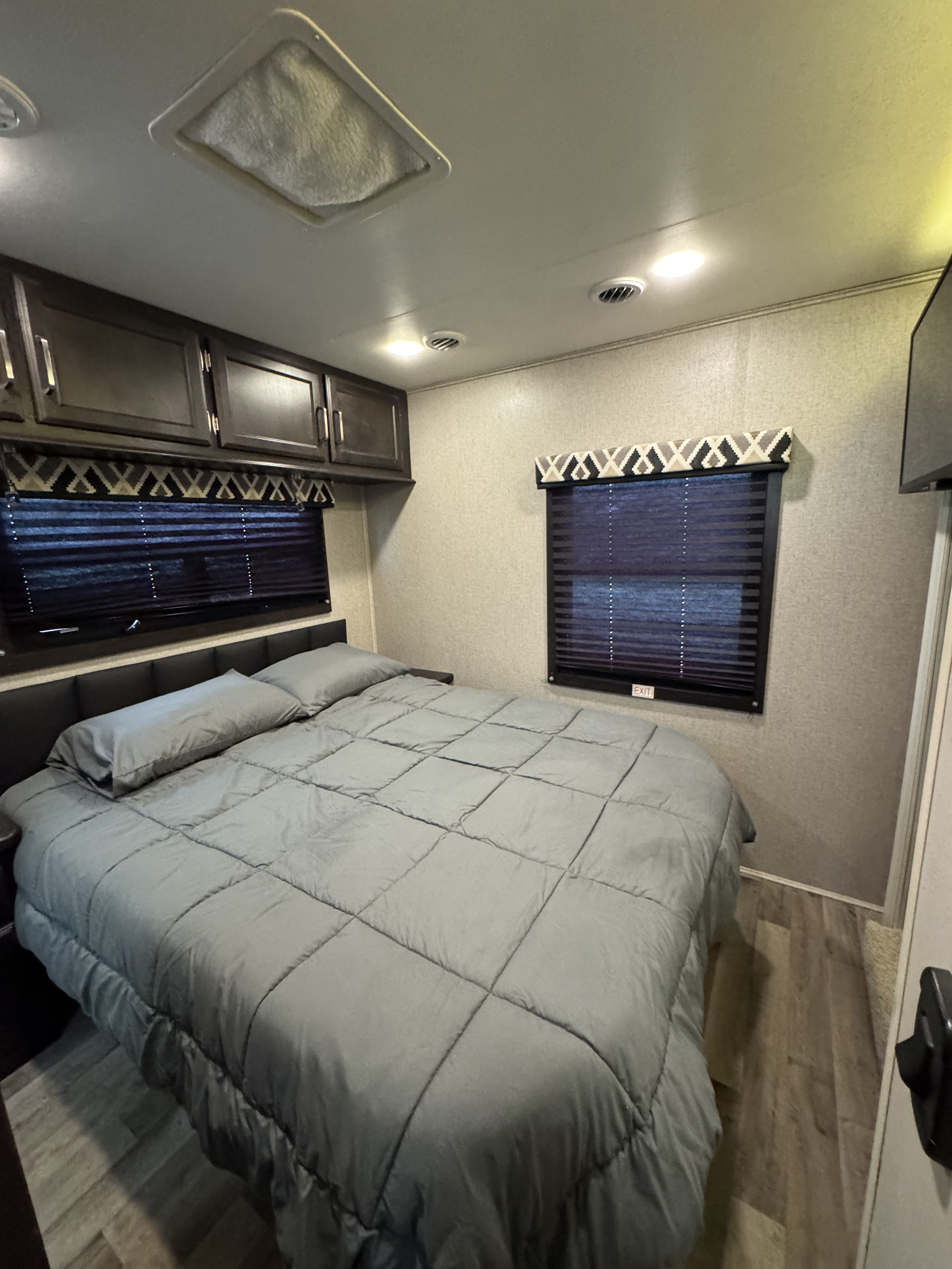 Cozy RV rental bedroom with a comfortable bed, overhead storage, and dual window blinds. Perfect for restful travel.. Entegra Coach Odyssey 2021