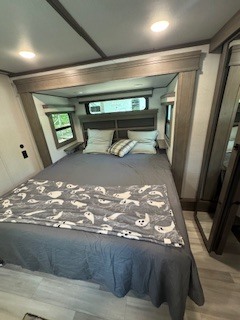 Cozy RV rental bedroom featuring a large bed with a fun ghost blanket, built-in nightstands, and two windows. Ideal for travel.. Grand Design Grand Design Fifth Wheel 2024