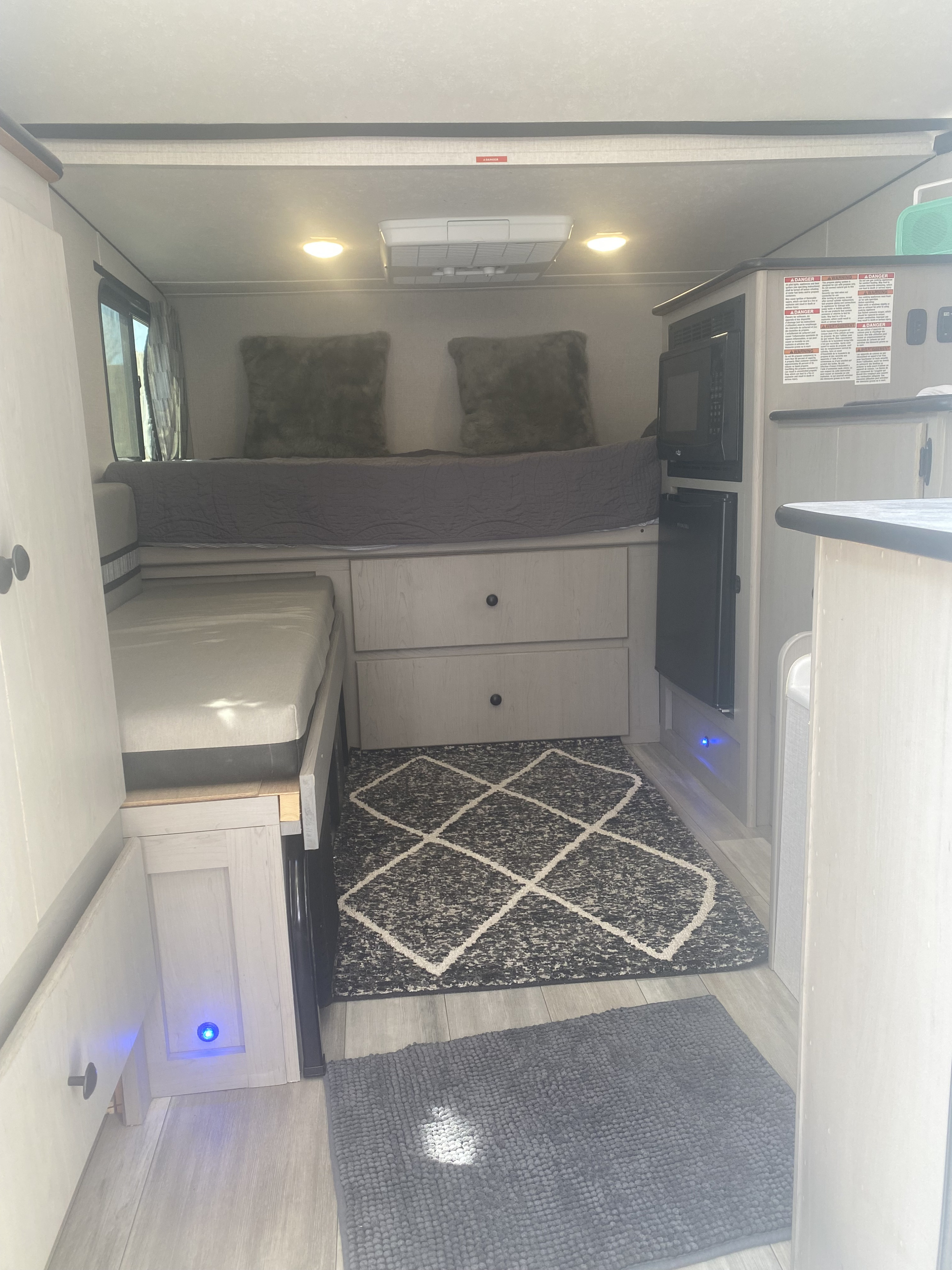 Compact RV rental interior boasts comfortable sleeping, a kitchenette, and smart storage, perfect for road trips.. Forest River Clipper 12.0 Pro 2023