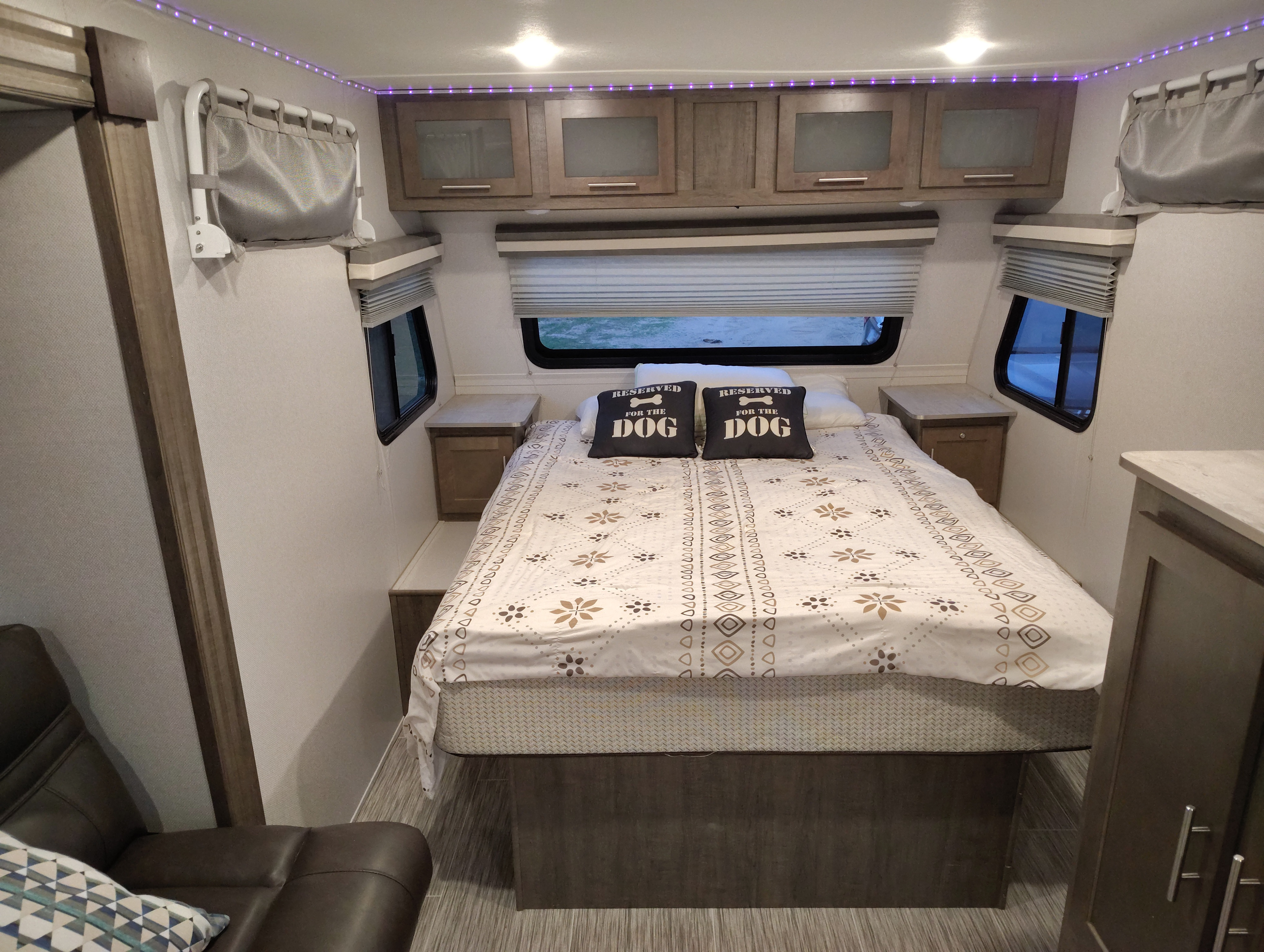 Comfortable RV rental bedroom with a cozy bed, dog pillows, and vibrant purple LED ambient lighting.. No Boundaries 19 2019