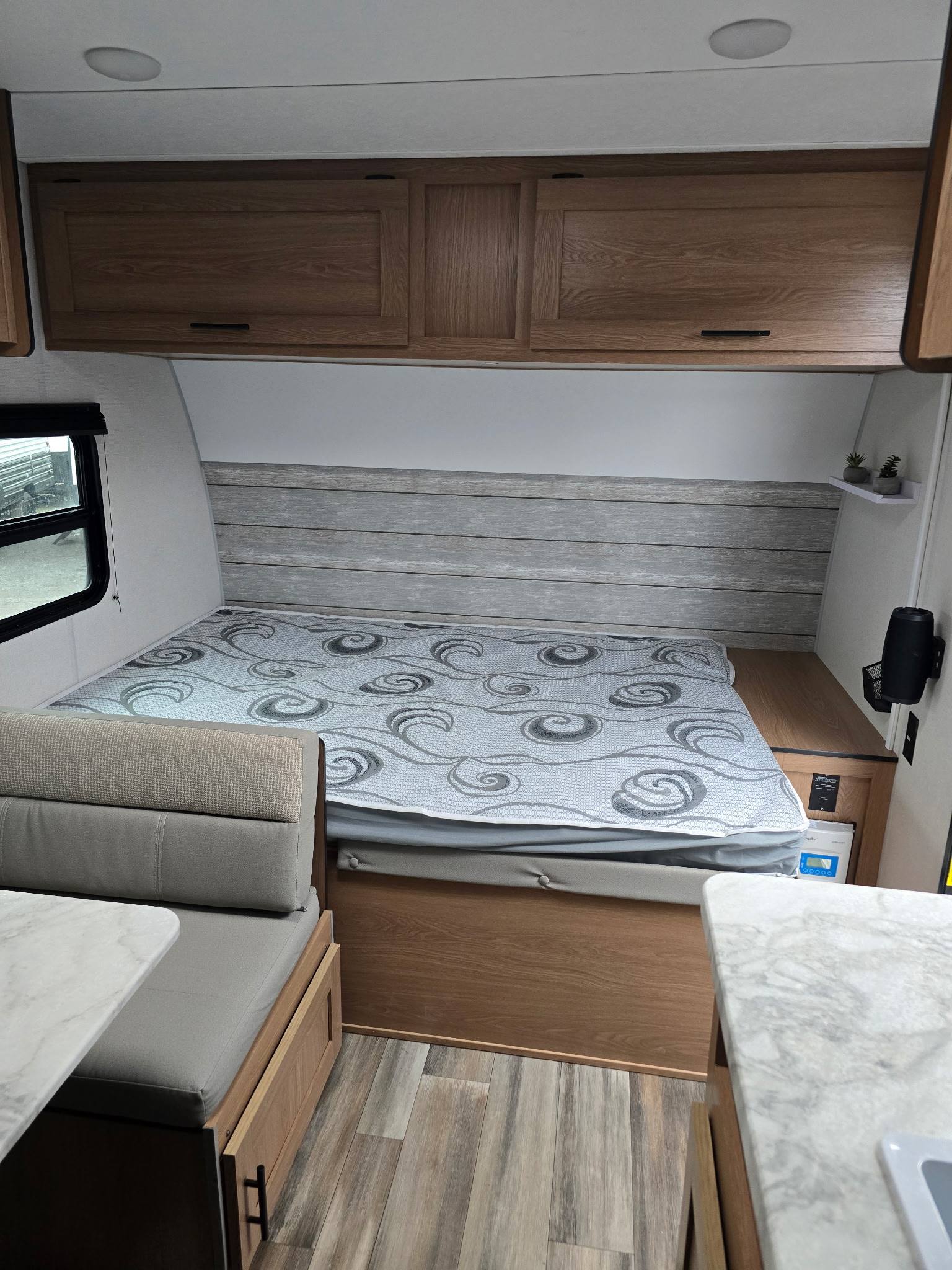 RV rental interior shows a cozy bed with patterned cover, wood cabinets, and dinette seating, perfect for travel.. Prime Time Avenger LT 16BH 2023