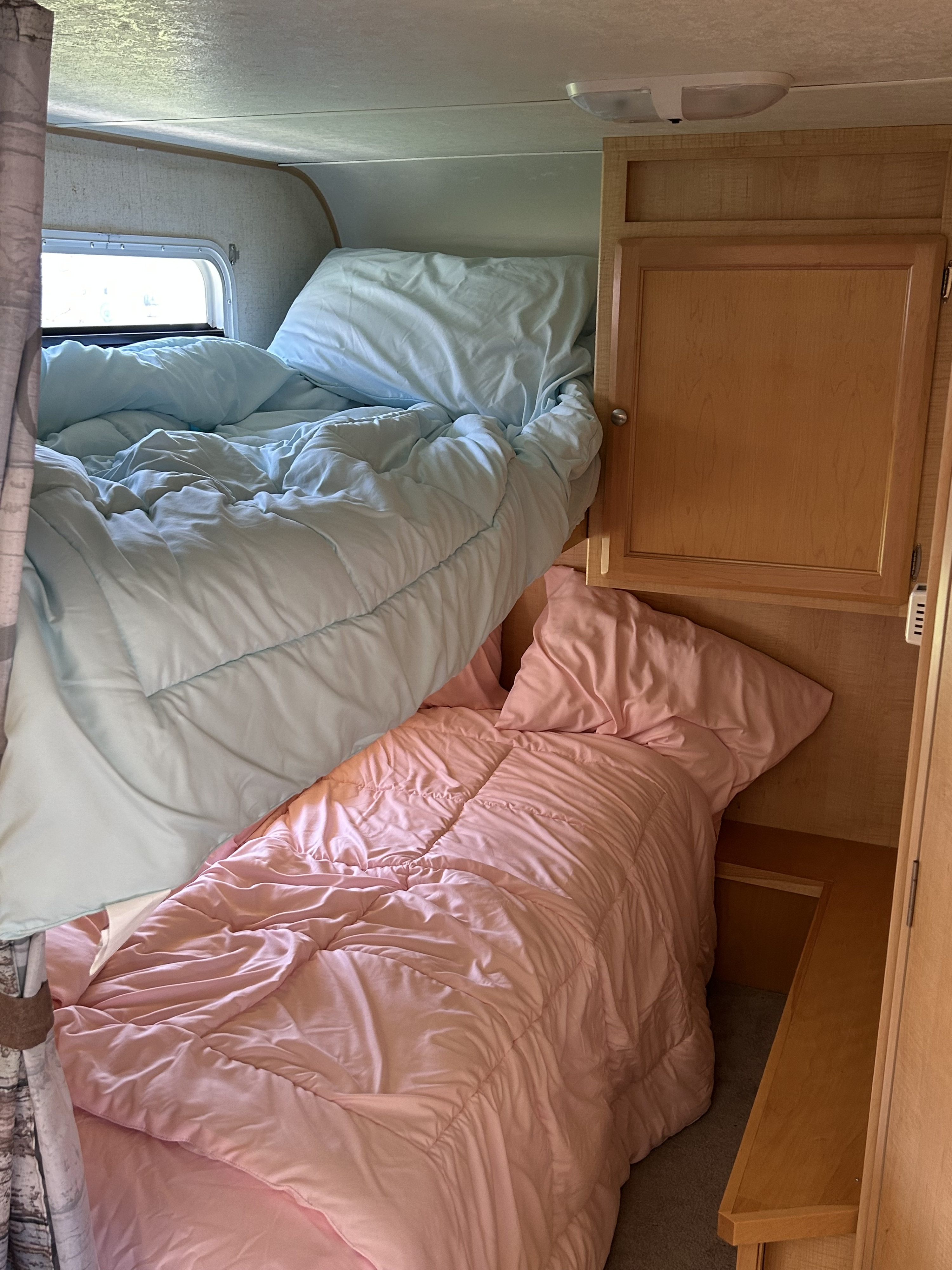 RV rental interior features cozy bunk beds with light blue and pink bedding. A compact, comfortable sleeping space.. R-Vision Trail-Lite 2005