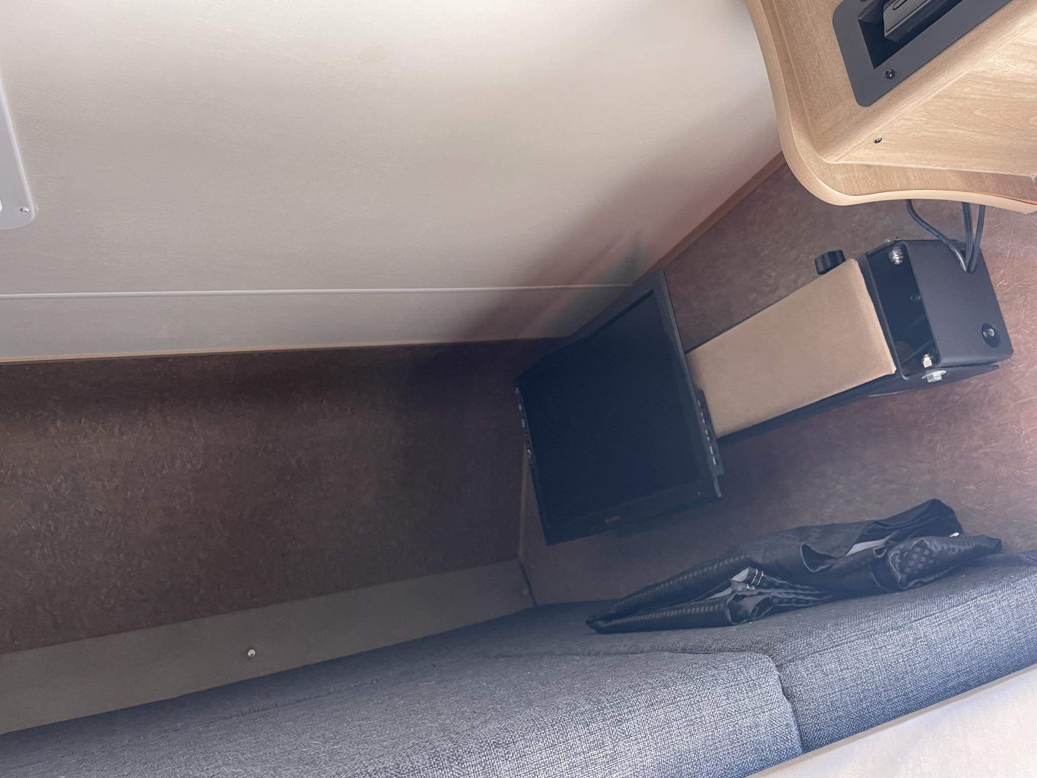Inside an RV rental: a compact sleeping area with a small TV mounted above a grey cushioned bed.. Forest River Coachmen Freelander 2015