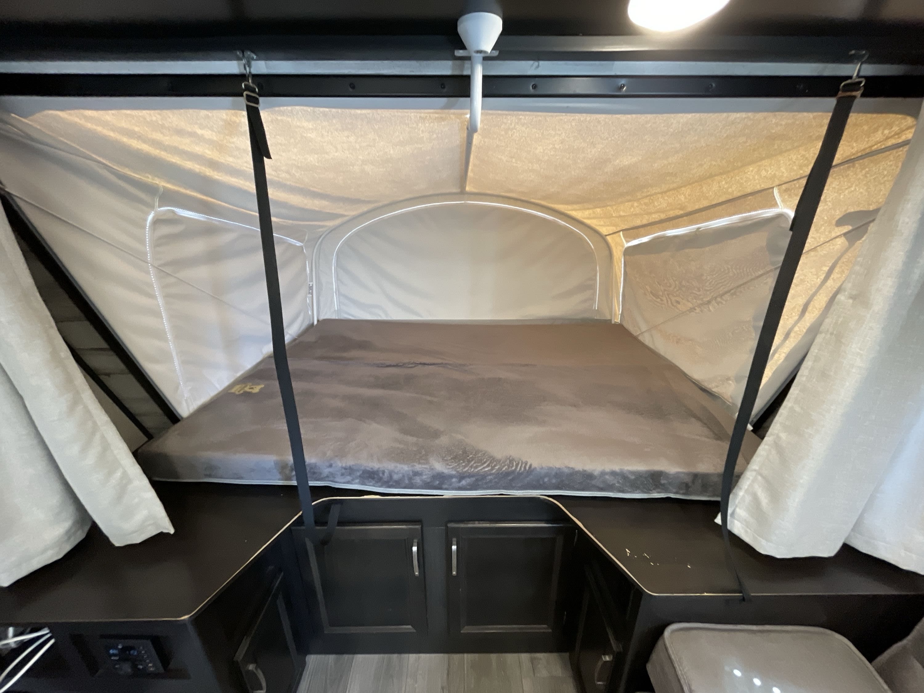 RV rental: Inside a pop-up camper featuring a large bed and light tenting, providing a compact, comfortable sleeping space.. Jayco Jay Feather 2020
