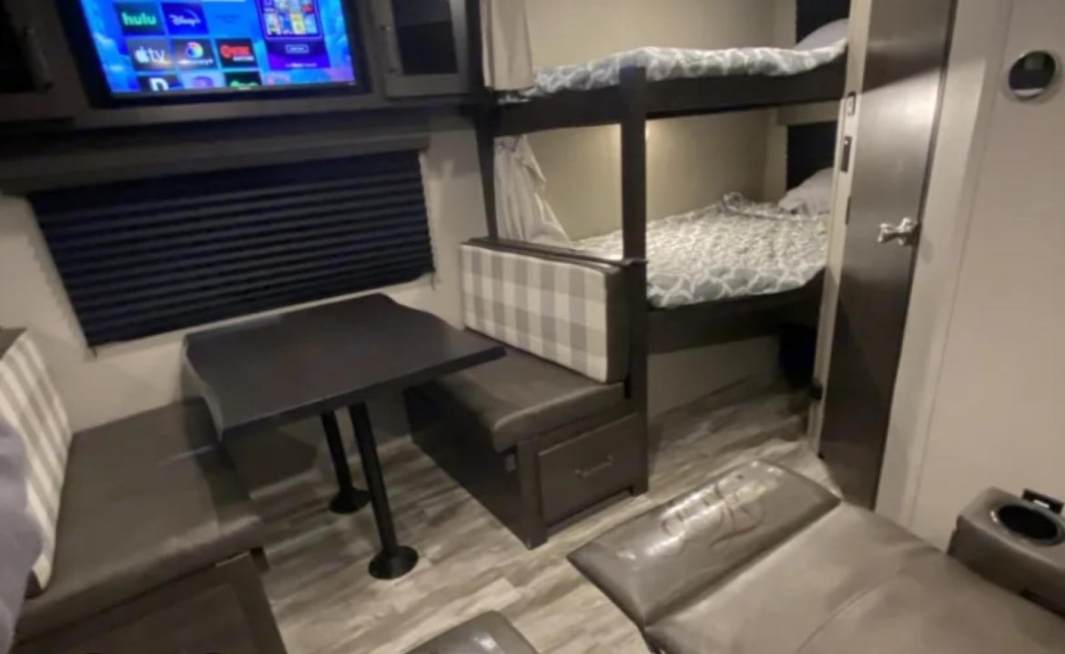RV rental with cozy dinette, bunk beds, and TV for entertainment. Plush seating offers comfort in this family-friendly camper.. Grand Design Transcend Xplor 2021