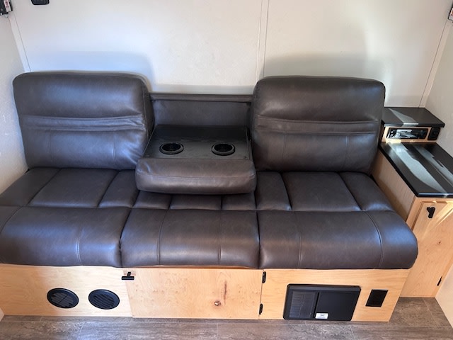 Inside your RV rental: a versatile sofa with cupholders, under-seat storage, and a media console for comfort.. Elusive Lo Pro Cabin 2023