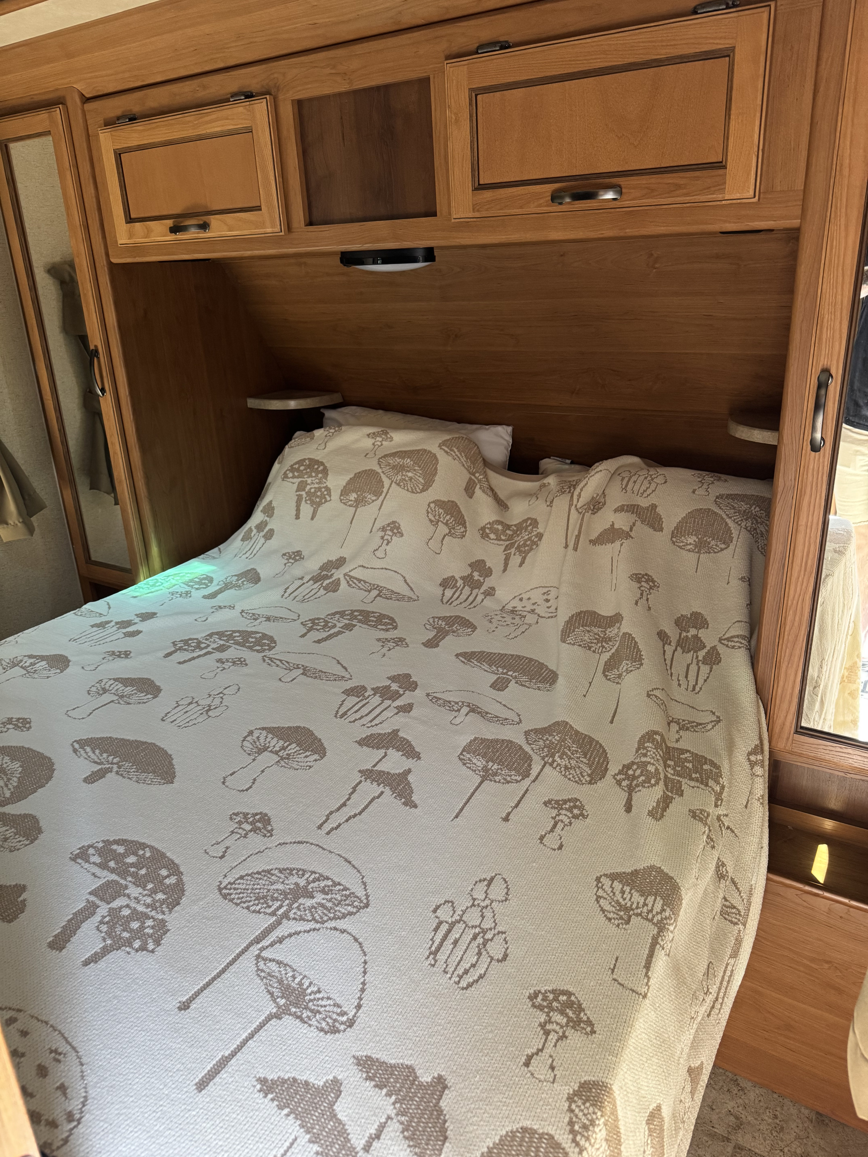 Cozy RV rental bedroom featuring a mushroom blanket, overhead cabinets, and built-in storage for travel comfort.. Crossroads RV Sunset Trail Super Lite 2017