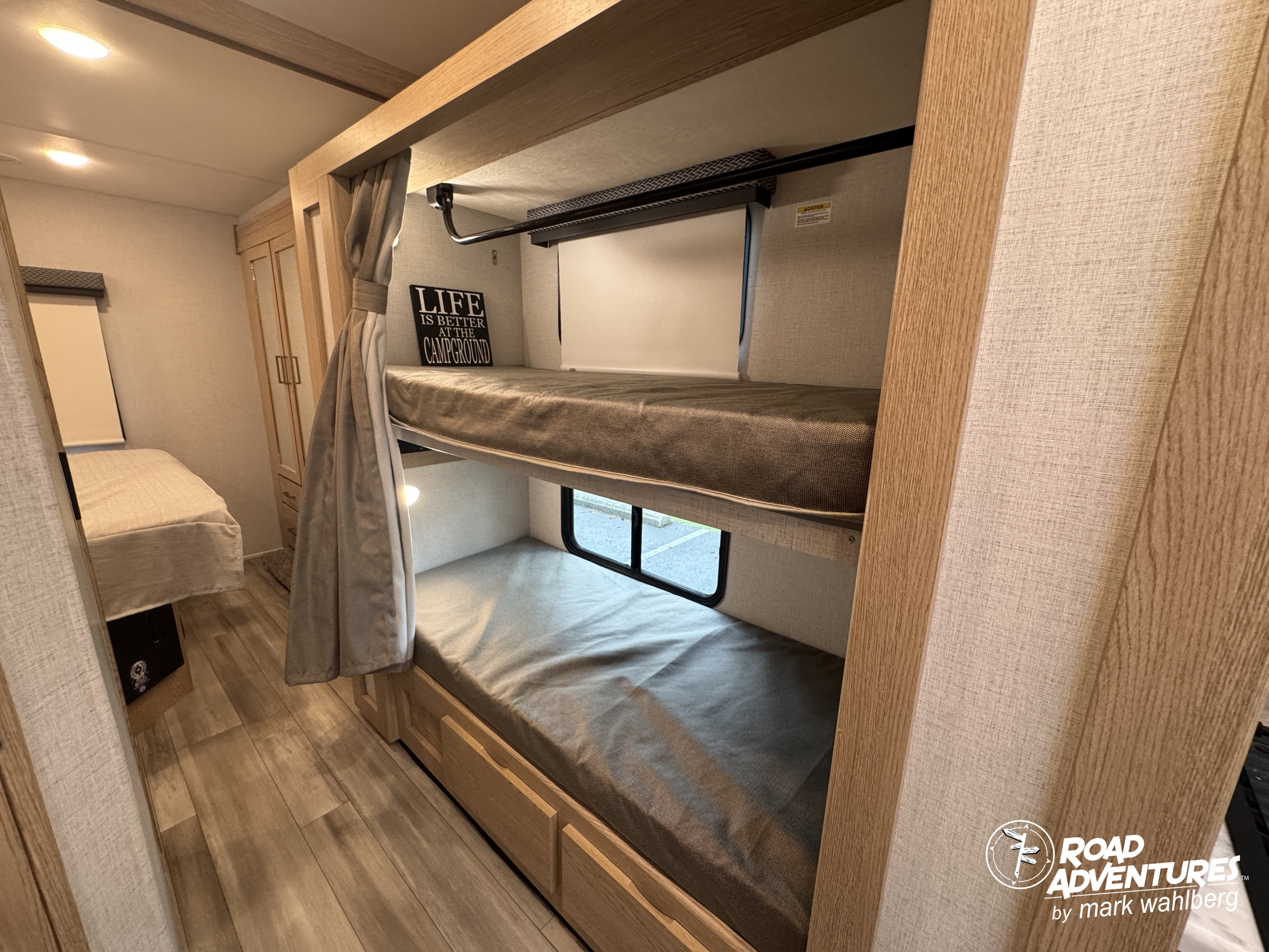 Cozy rv rental interior featuring comfortable bunk beds with light wood accents and a window, ideal for family camping trips.. Thor Motor Coach Four Winds 2026