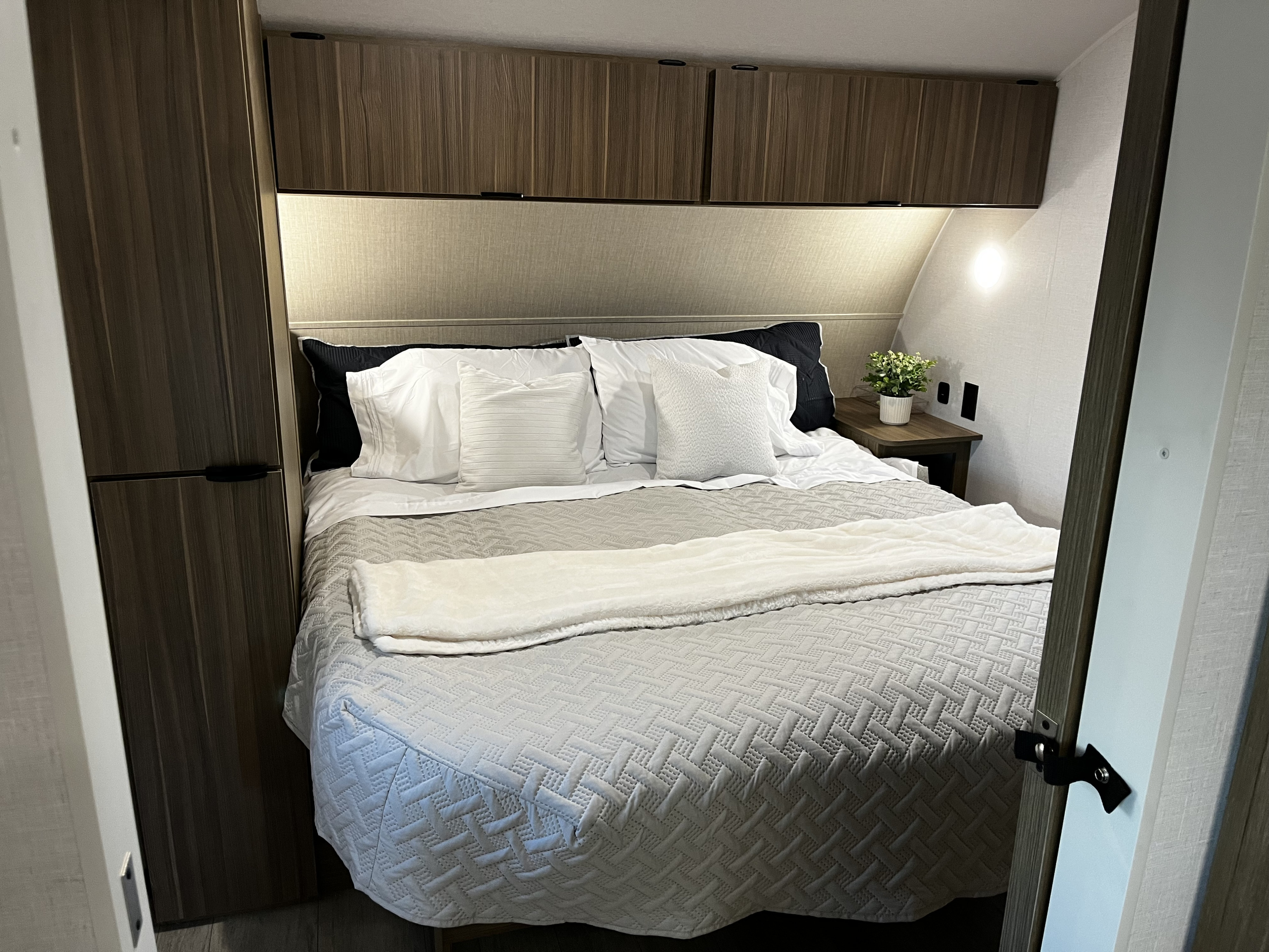 Modern RV rental bedroom featuring a comfy bed, wood cabinets, and built-in lighting.. Salem Cruise Lite 26ICE 2025