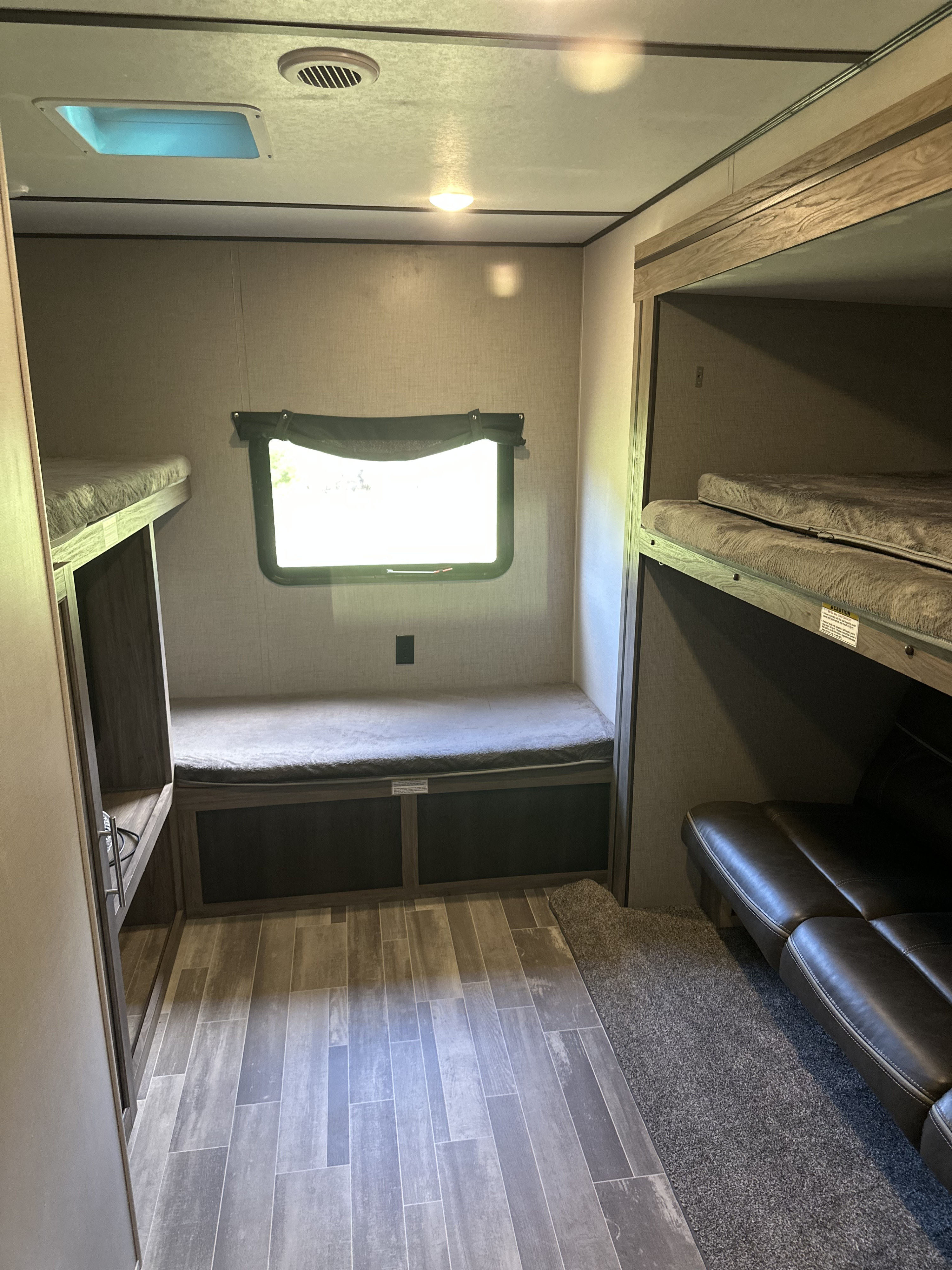 Spacious RV rental interior featuring multiple bunk beds, a versatile seating area, and durable flooring for comfortable stays.. Crossroads RV Zinger 2020