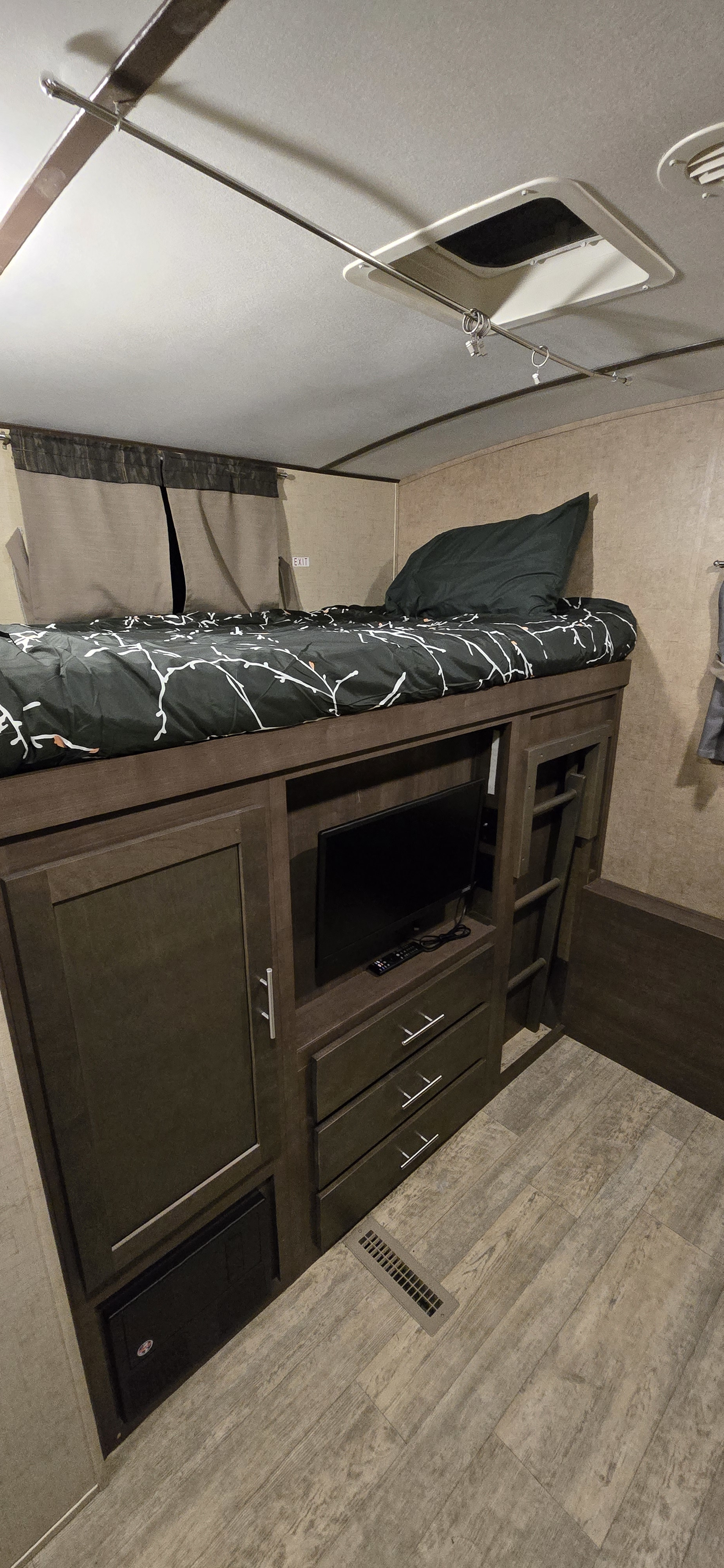 RV rental bunk bed setup with TV, storage, and ladder. Cozy sleeping area in a camper.. Forest River Surveyor 2016