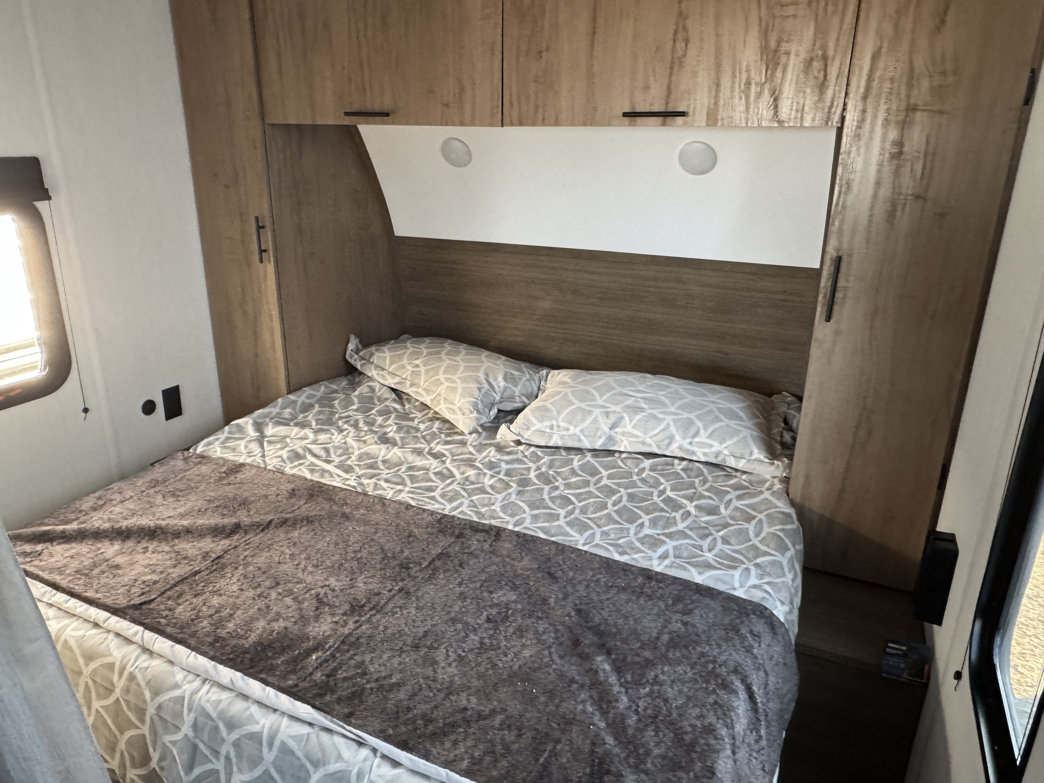 Cozy RV rental bedroom featuring a comfortable bed with patterned bedding, built-in storage, and ambient lighting.. Forest River 20RDSE 2025