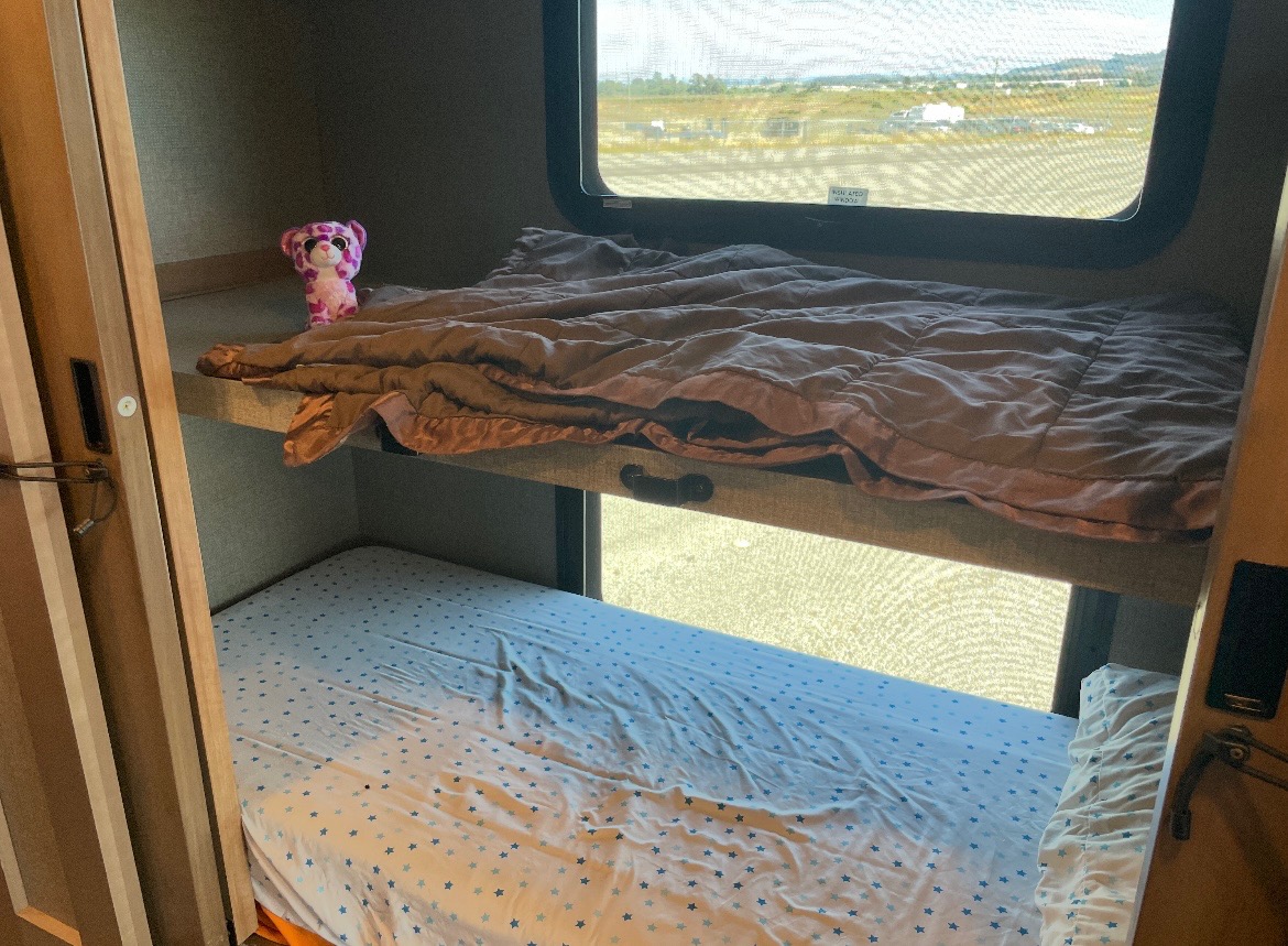 Cozy bunk beds inside an RV rental, featuring a pink leopard plush on the top and a starry sheet below.. Mirimar 34.8 2022