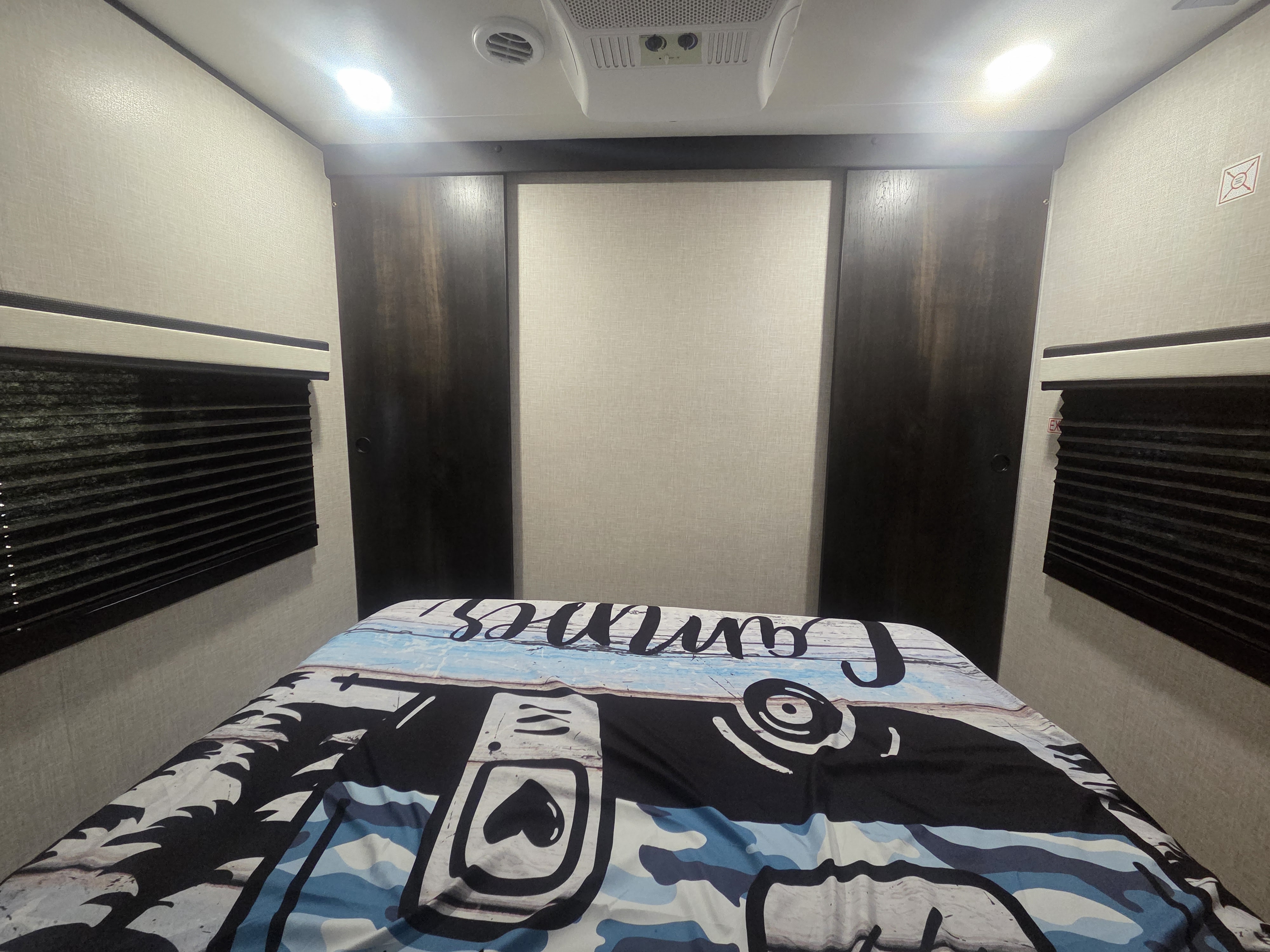 Cozy RV rental bedroom with patterned comforter, sliding wardrobes, and window blinds. Features overhead AC & lighting.. Jayco Jay Flight 2024