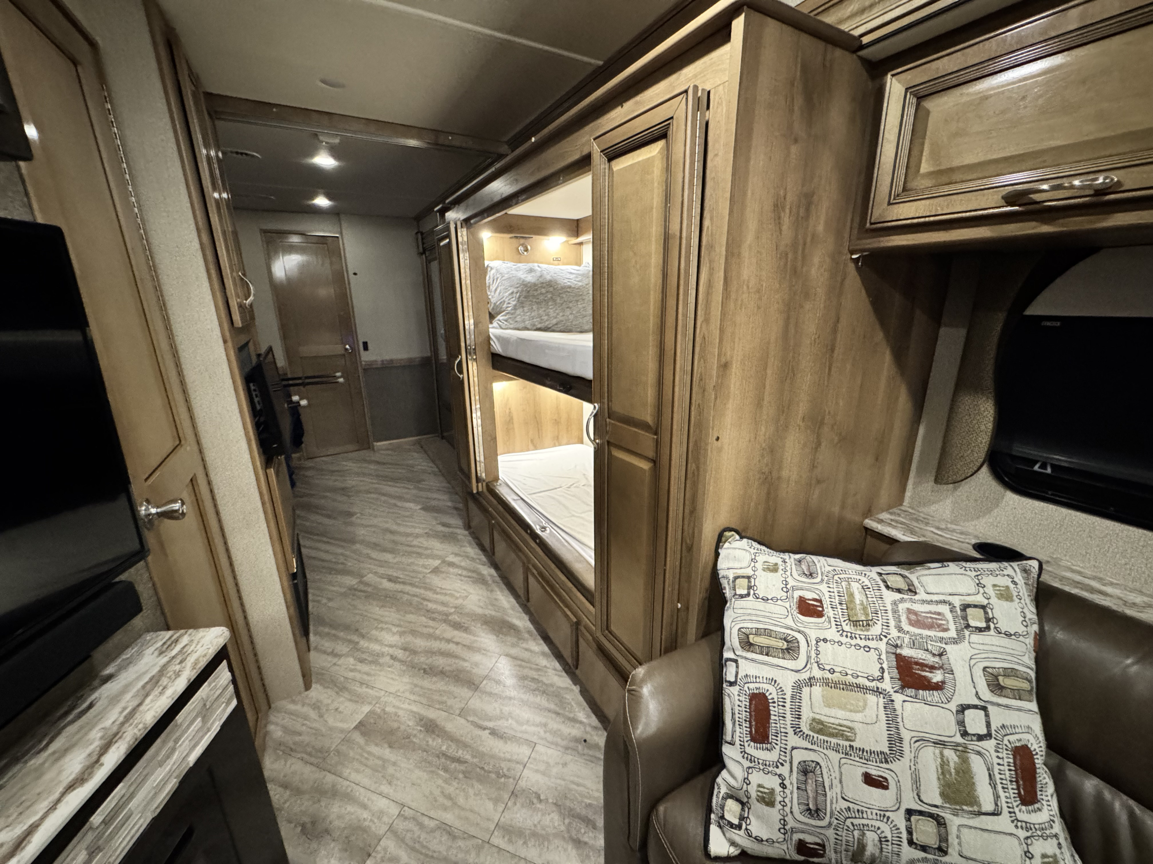Cozy RV rental interior with bunk beds, a comfy seating area, and a hallway. Perfect for family adventures and travel.. Fleetwood Bounder 2019