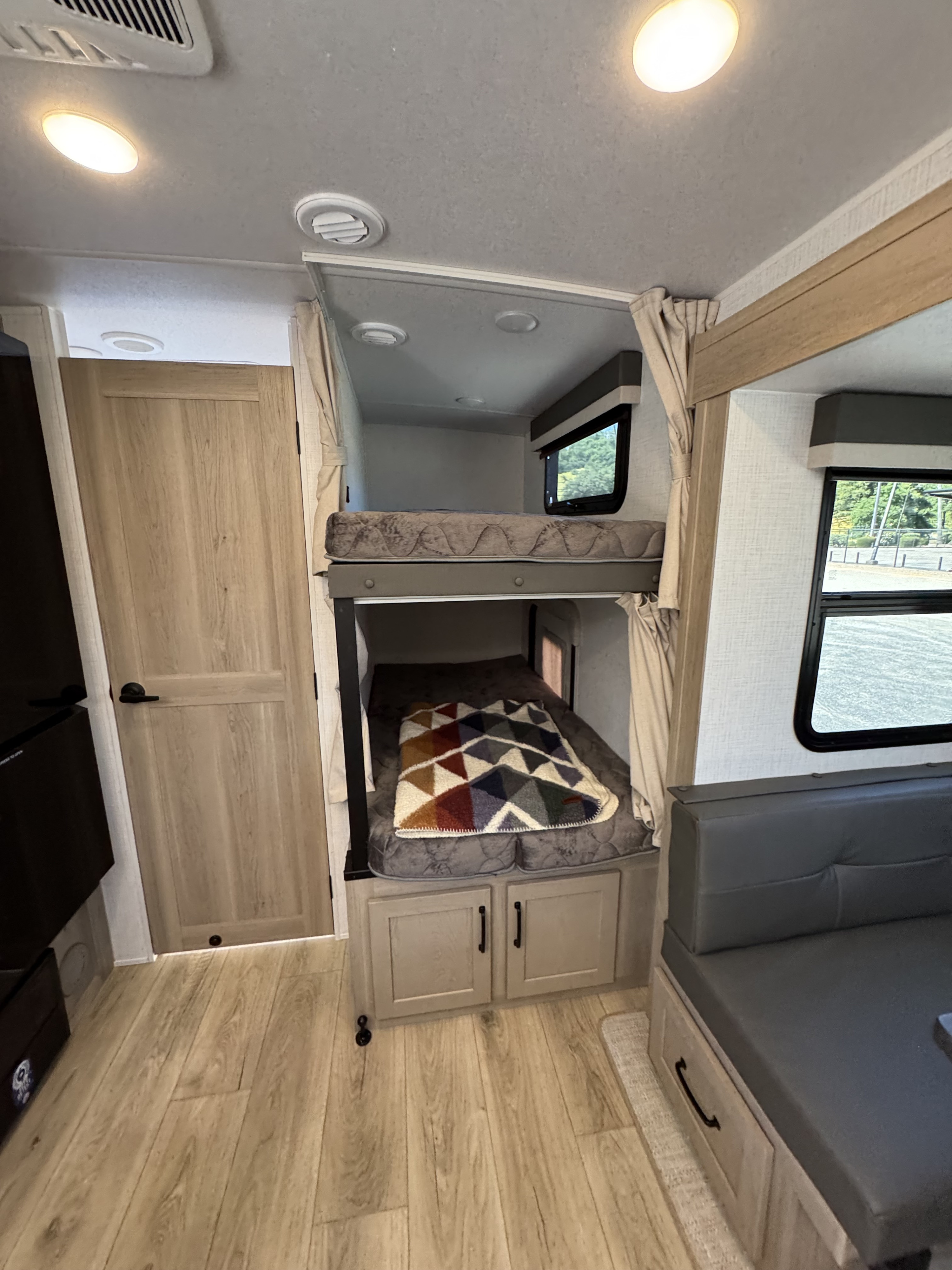 RV rental interior: cozy bunk beds, light wood floors, and seating area with a view. Ideal for your next adventure.. Flagstaff Micro Lite 25DBH 2025