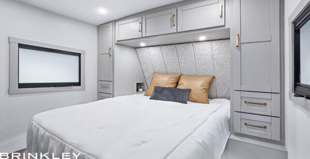 This bright, modern RV bedroom, great for an rv rental, offers smart storage cabinets, a bed, and a wide window.. Brinkley Air 295 2025