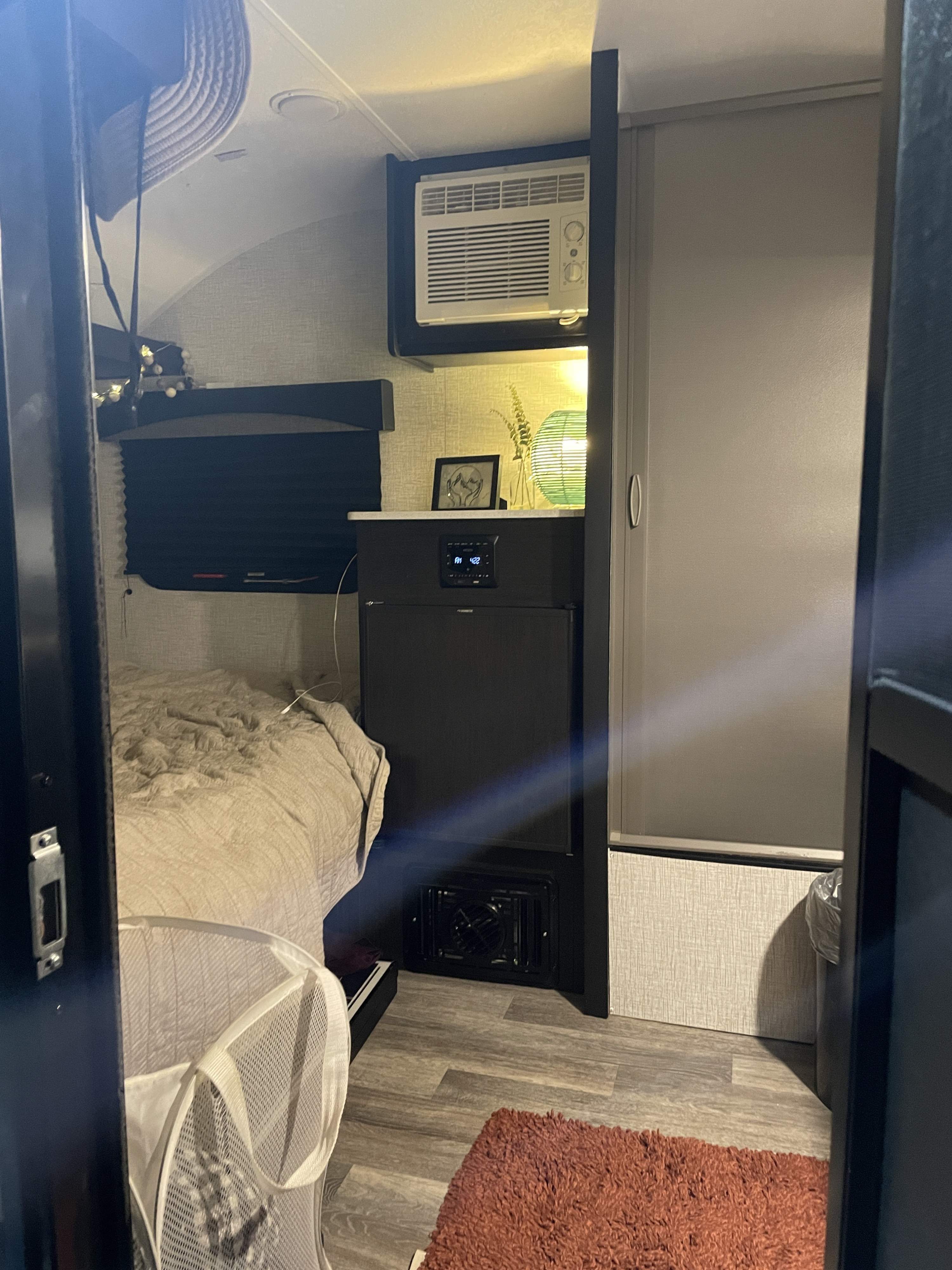 Cozy RV rental interior: bedroom view with a bed, AC unit, and compact amenities like storage & a closet.. Braxton Creek Bushwhacker Plus 2021
